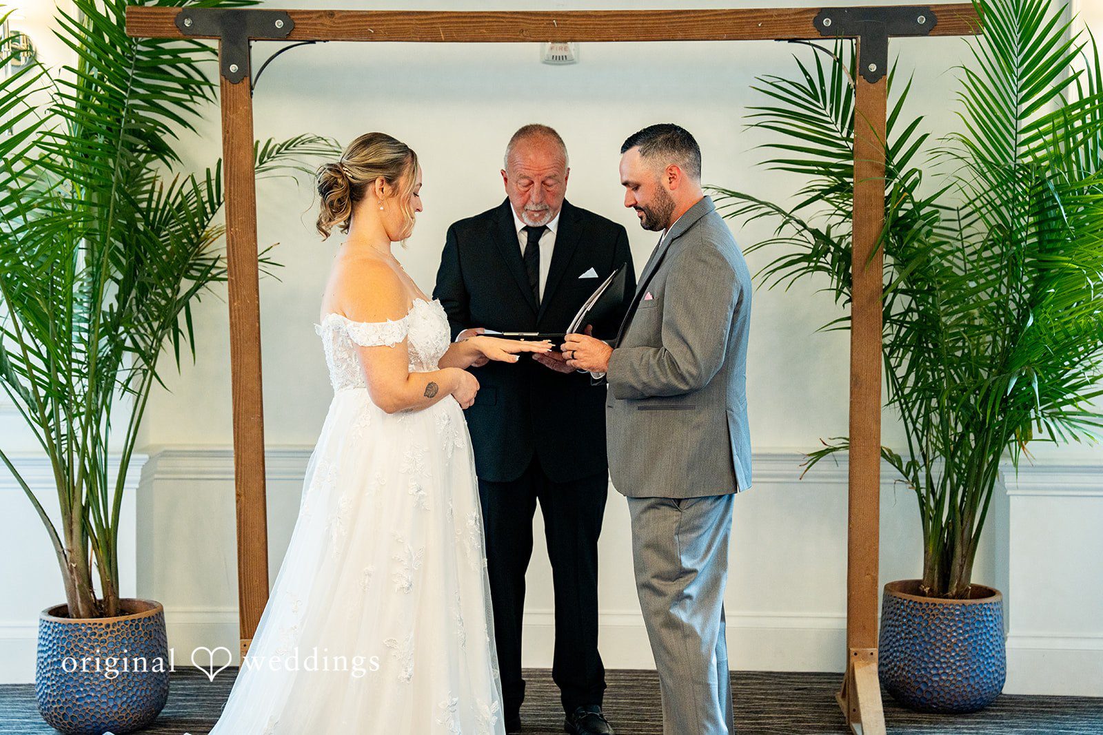 Alex + Courtney A bride and groom exchanging vows before an officiant.