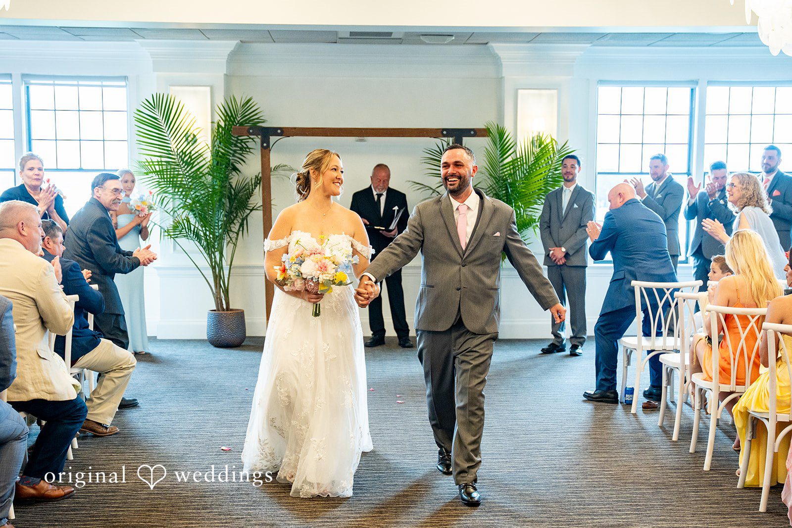 Alex + Courtney A bride and groom walking down the aisle while guests applaud.