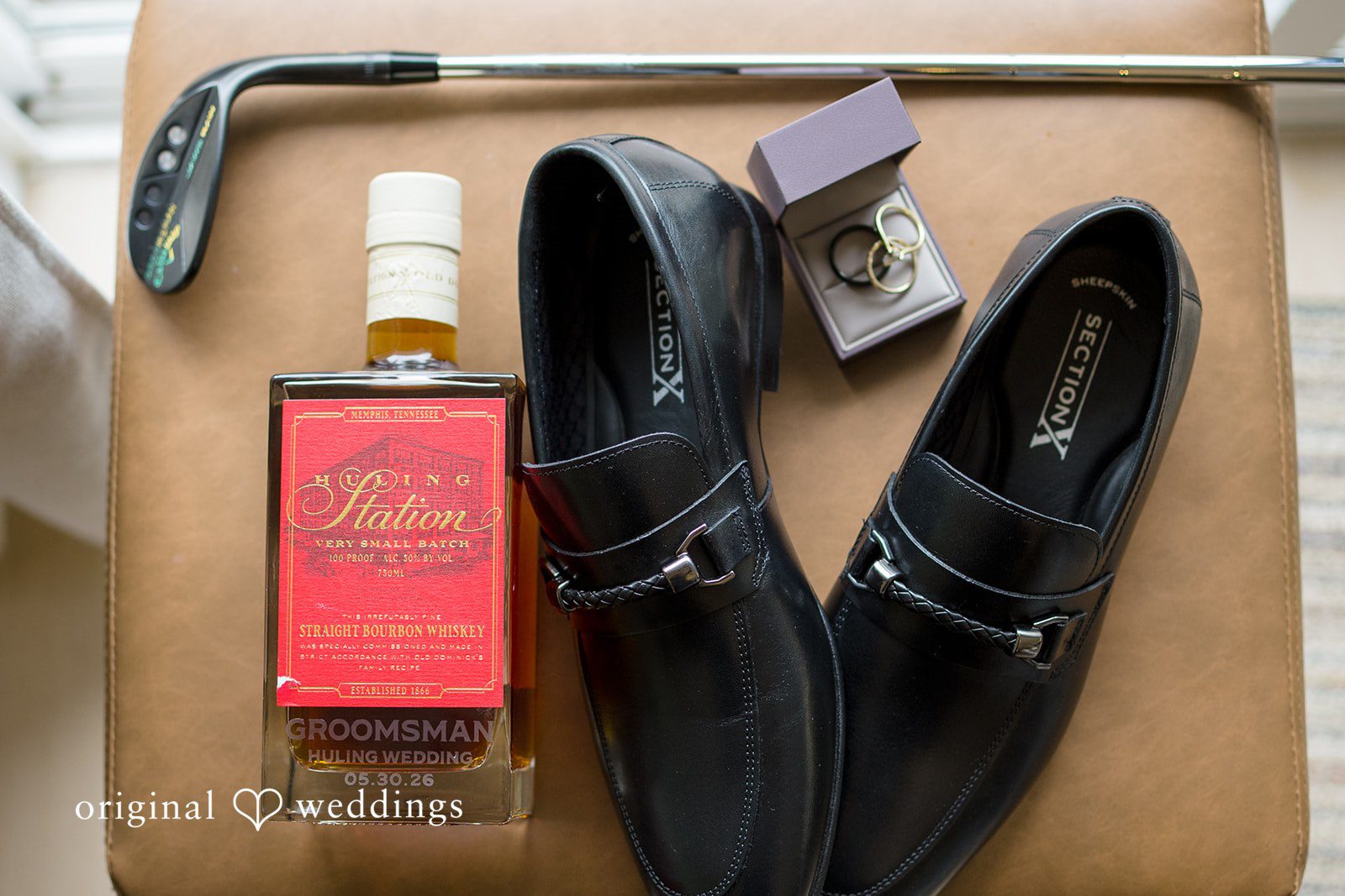 Alex + Courtney A glass bottle of liquor sitting next to black dress shoes.