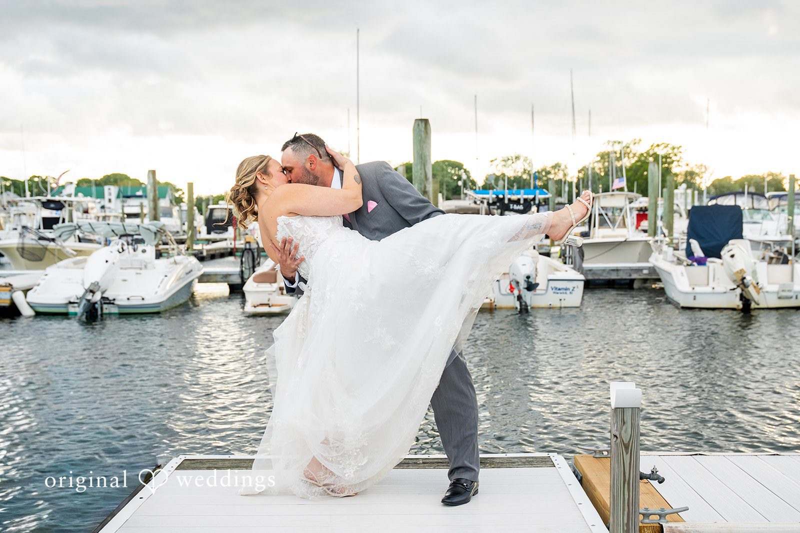 Alex + Courtney A groom carrying his bride in his arms on a dock.
