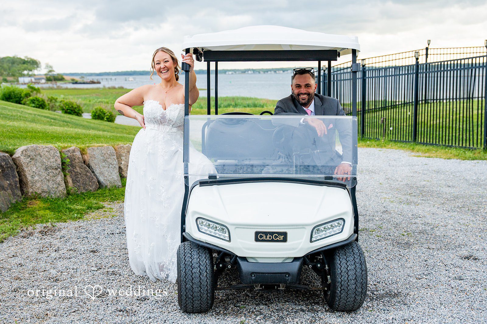 Alex + Courtney A bride standing next to a golf cart on a path.