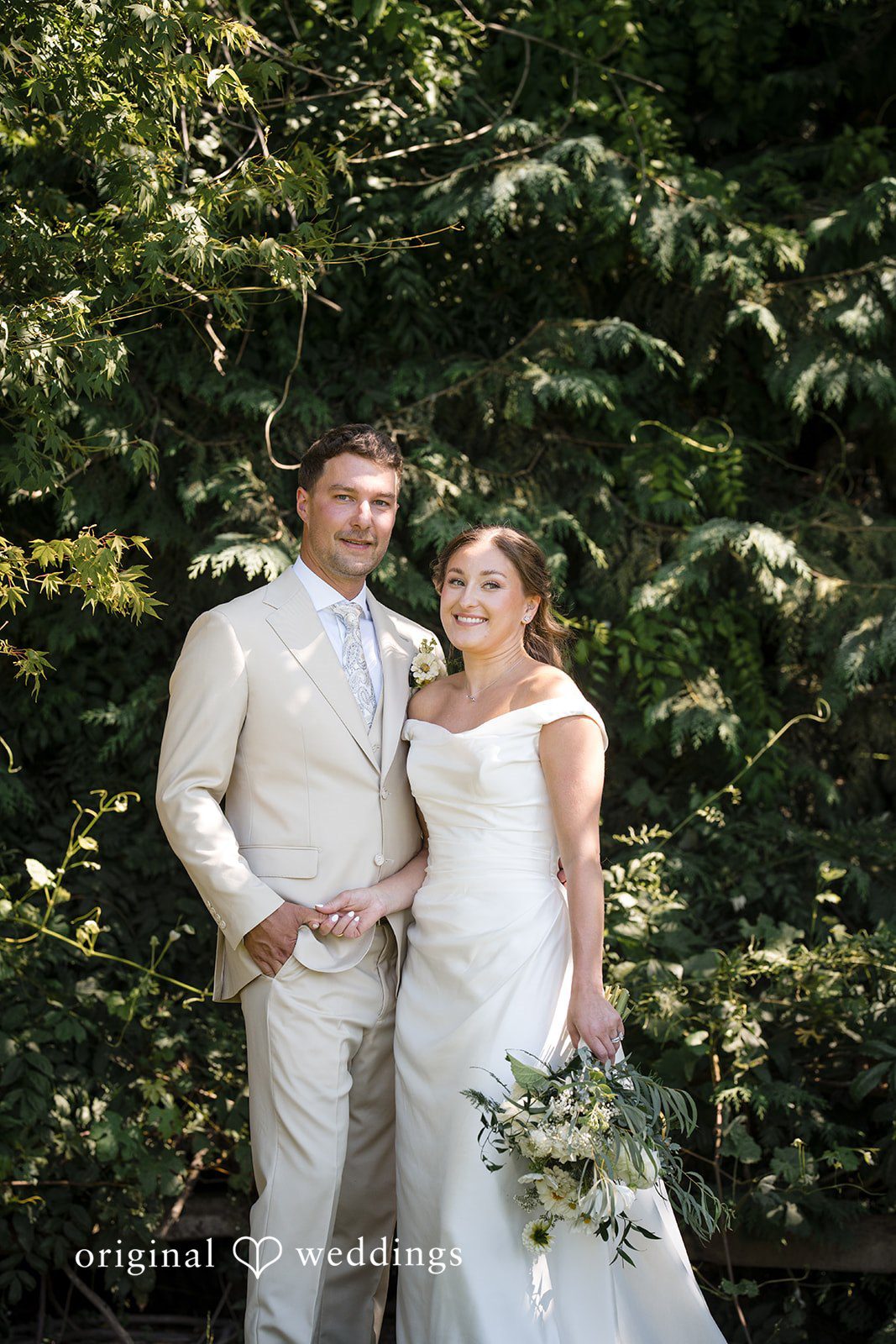 Hanna + Austin A bride and groom standing side-by-side in front of greenery.