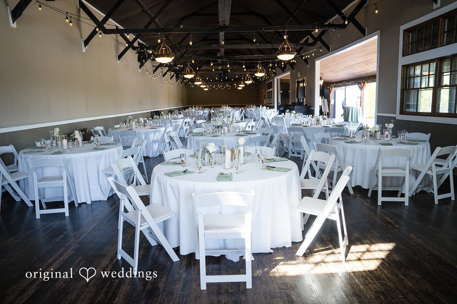Hanna + Austin Round reception tables with white linens and white chairs.