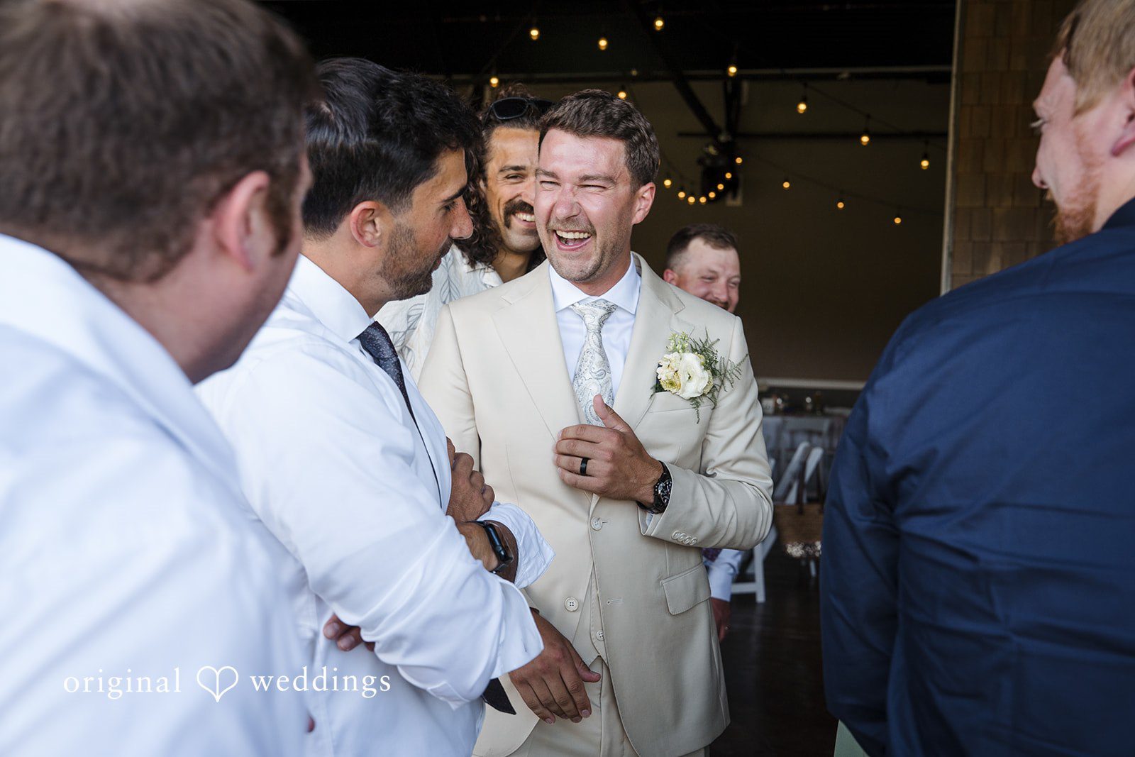 Hanna + Austin A groom smiling while talking to guests at a wedding event.