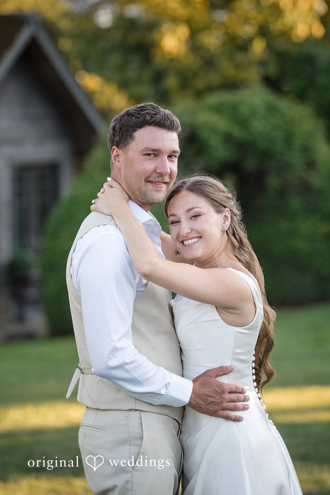 Hanna + Austin A groom embracing his bride from behind as they both smile warmly.