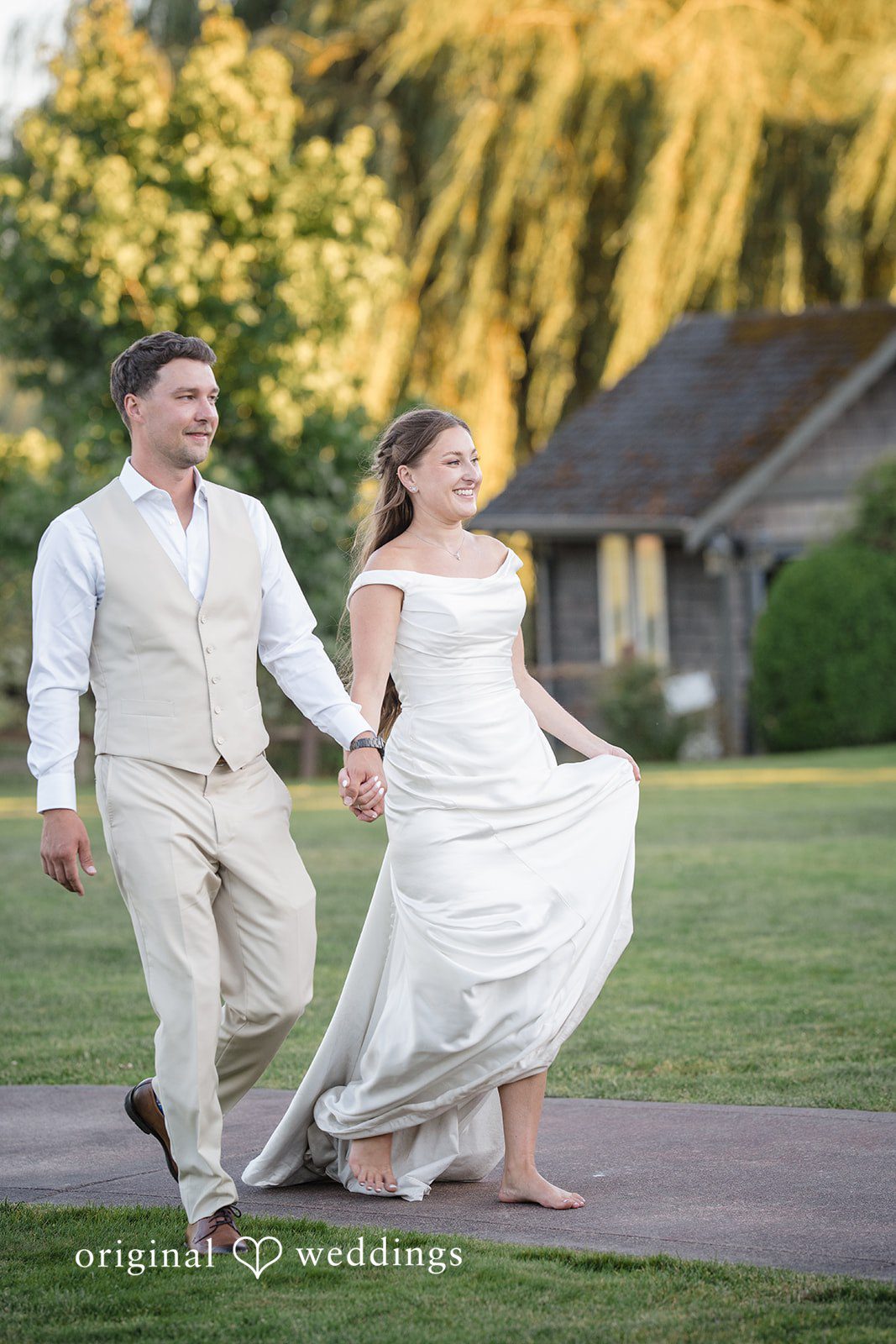 Hanna + Austin A bride and groom holding hands while walking across a green lawn.