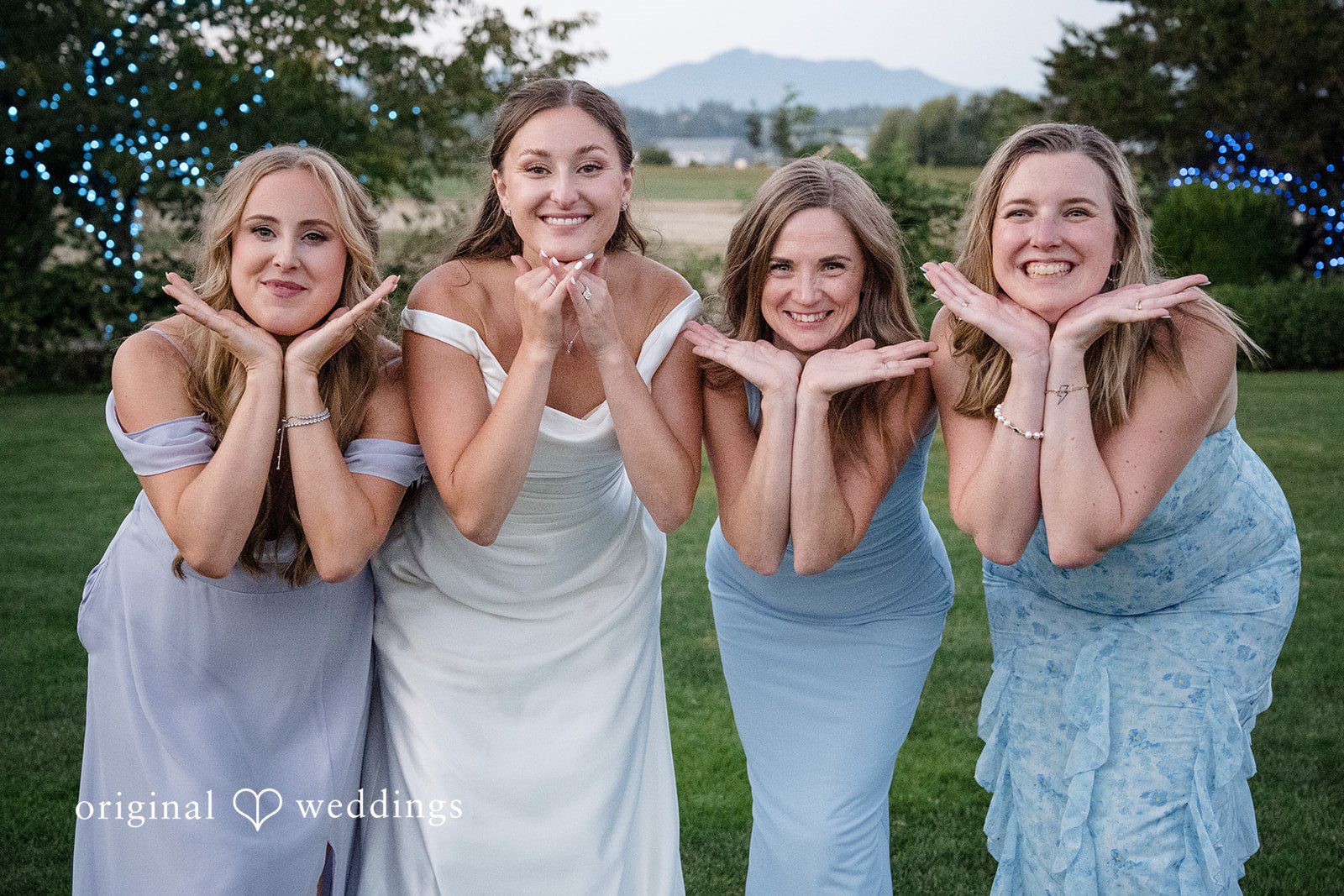 Hanna + Austin Bridesmaids in blue dresses posing with their hands framing their faces.