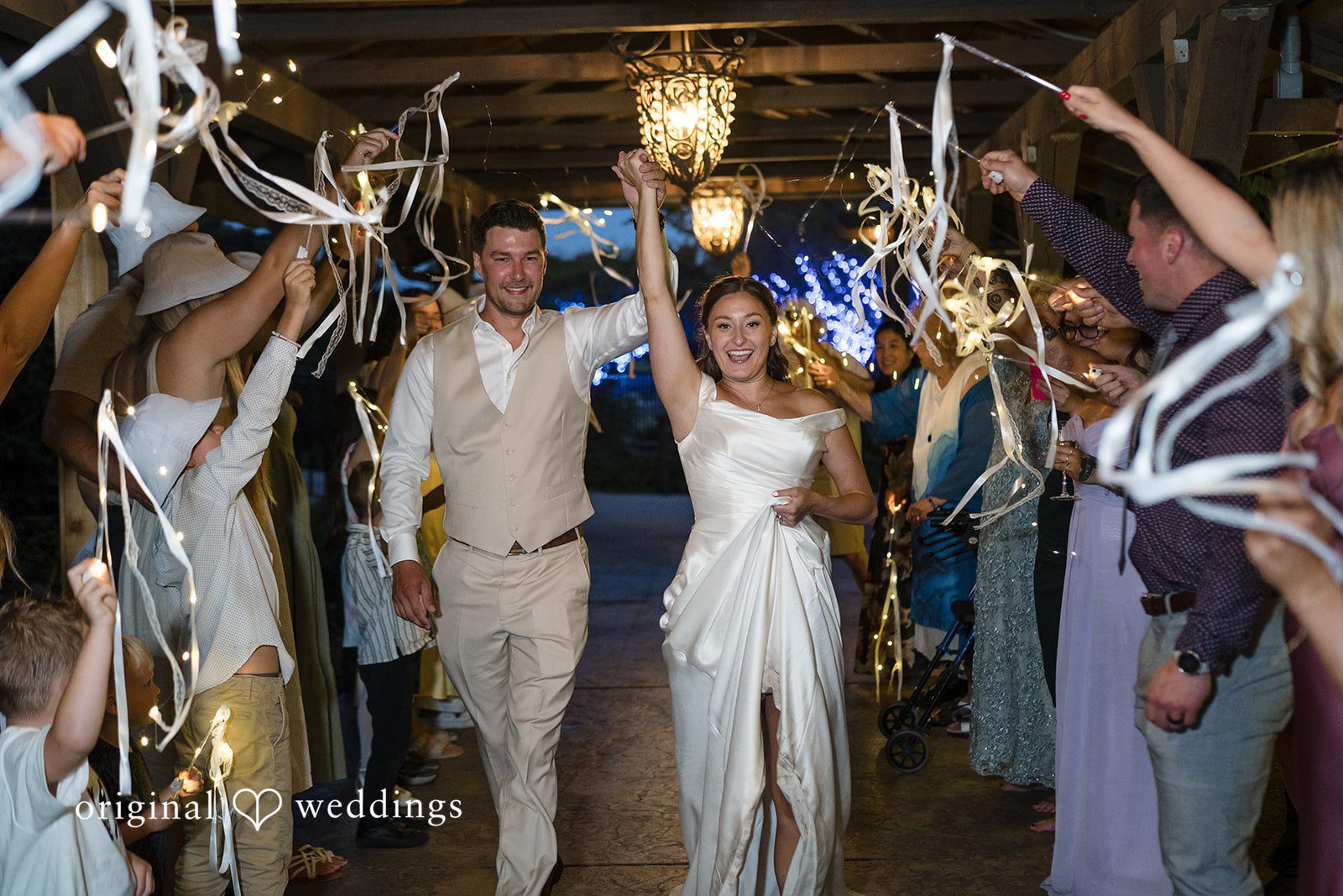 Hanna + Austin A bride and groom walking through a grand exit surrounded by wedding guests.