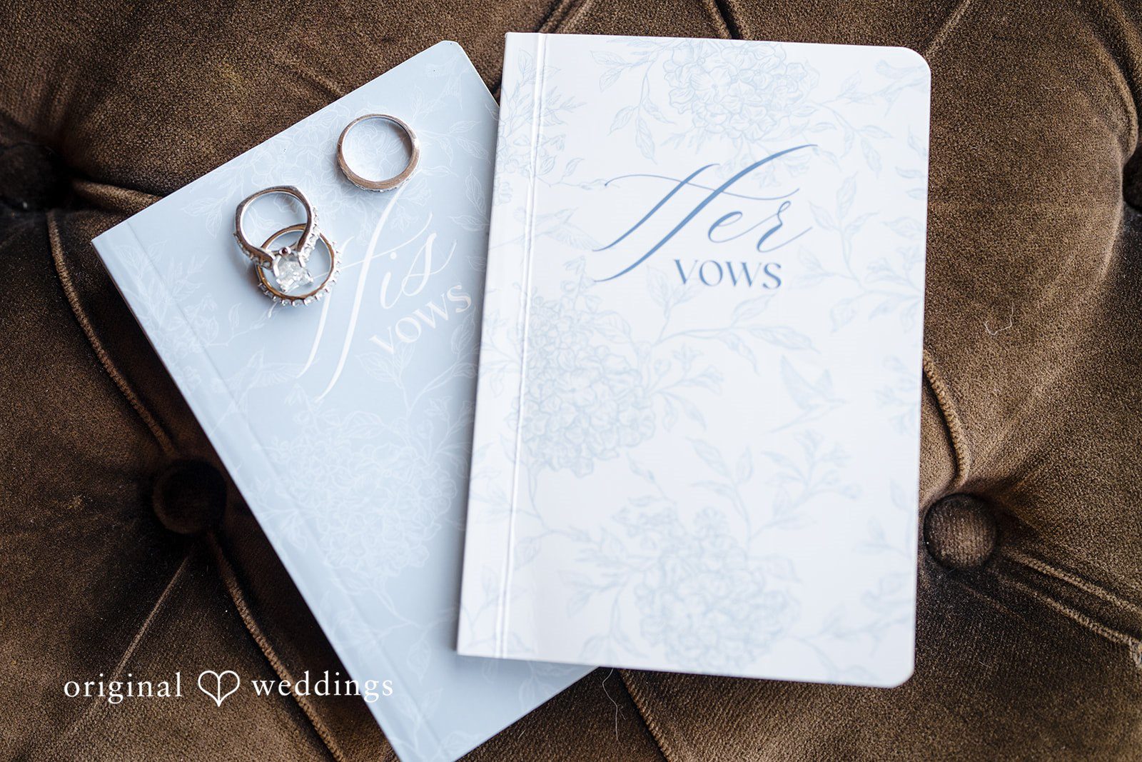 Hanna + Austin Closed white menu folder beside two silver wedding rings.