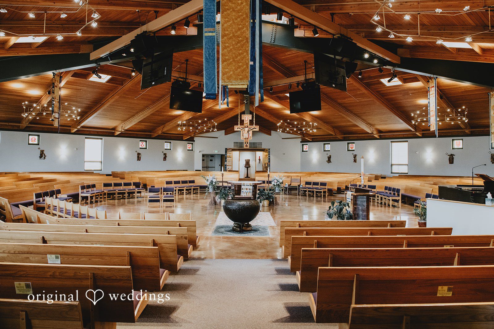 Empty church sanctuary with wooden pews facing an altar decorated with floral arrangements.