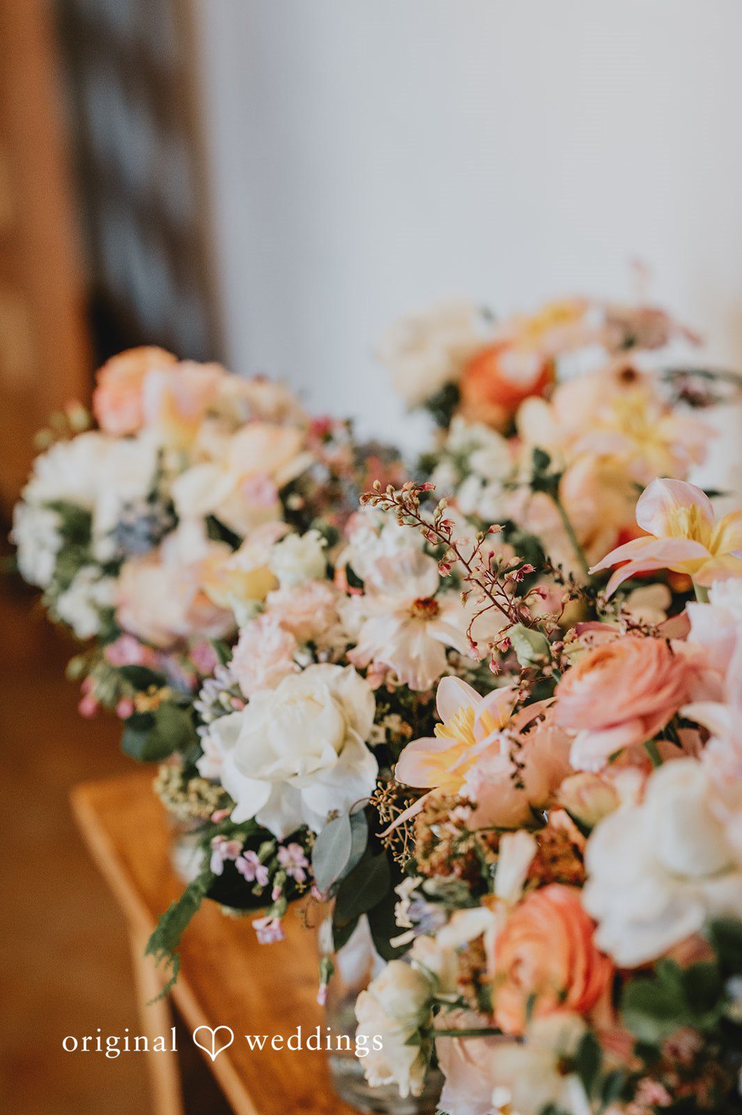 Close-up of a vibrant floral arrangement featuring peach, pink, and white blossoms with greenery.