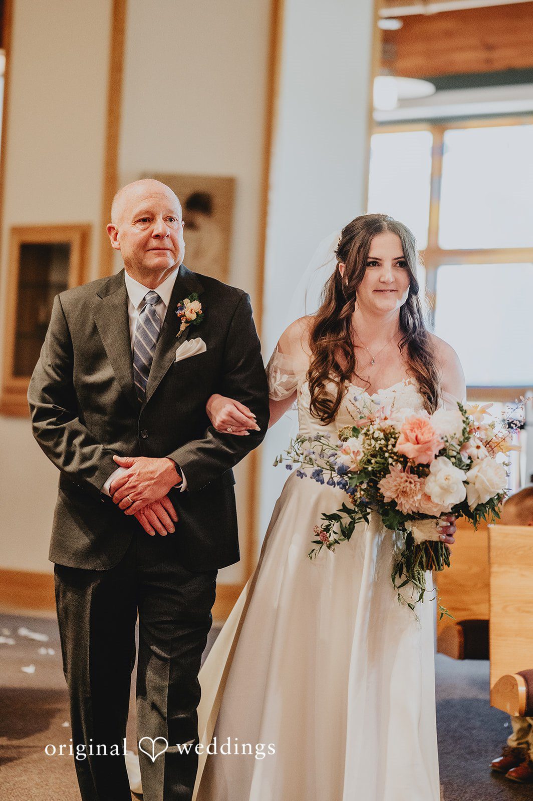 Bride walking down the aisle arm-in-arm with an older man.