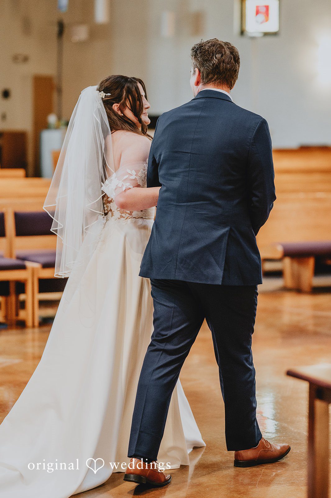 Rear view of a bride and groom walking toward the altar.