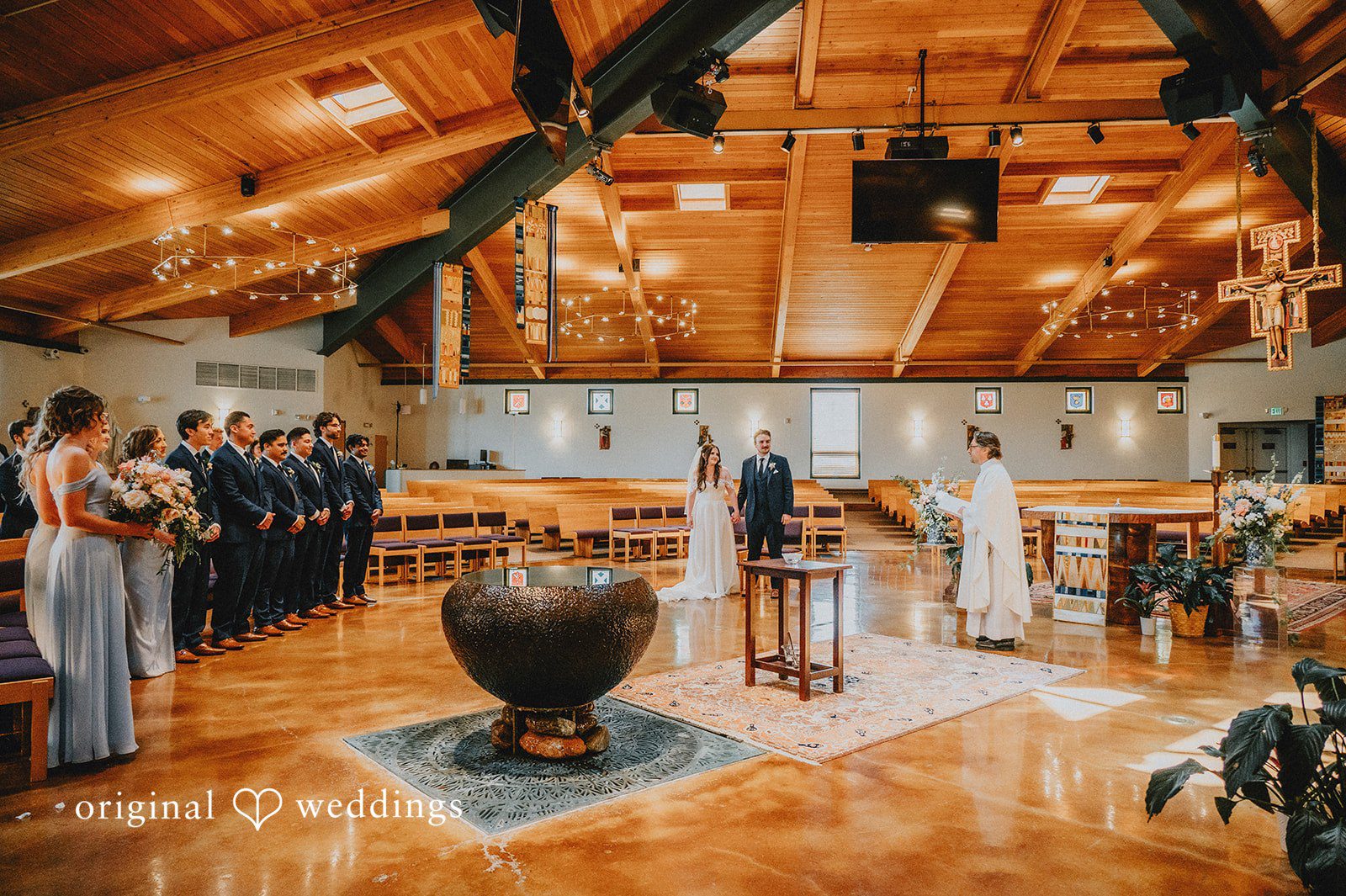 Wide view of a wedding ceremony taking place inside a wooden chapel.