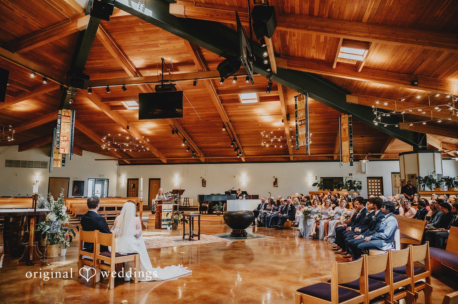 Bride and groom seated at a table during the chapel ceremony.