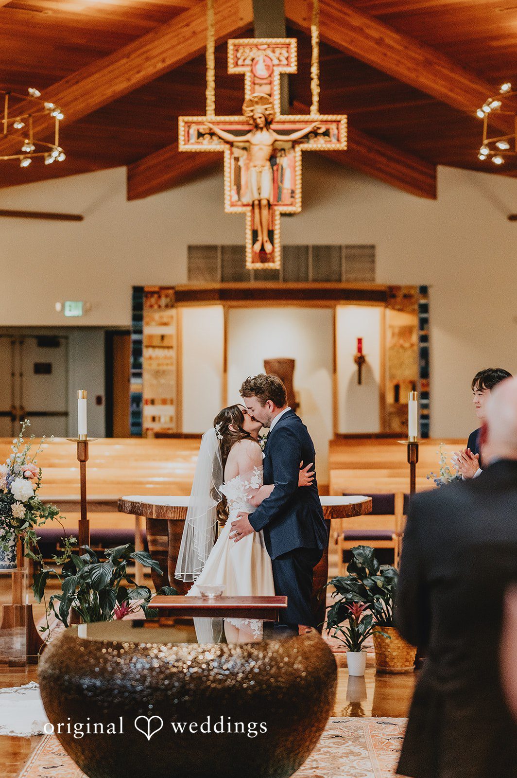 Bride and groom sharing their first kiss at the altar.