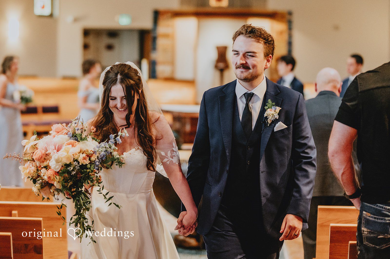 Newlyweds walking down the aisle together smiling after the ceremony.