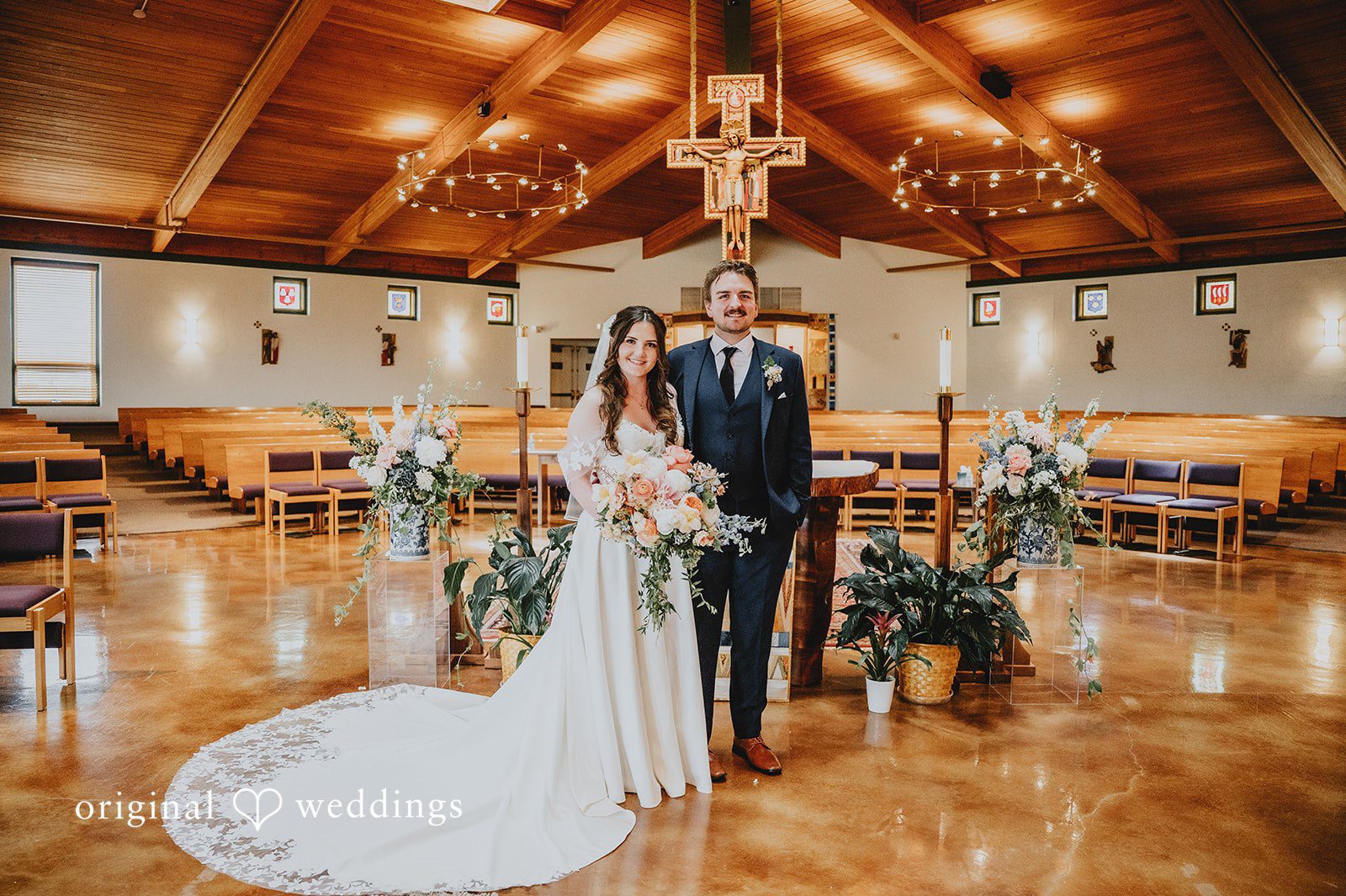 Bride and groom posing together at the altar of an empty chapel.