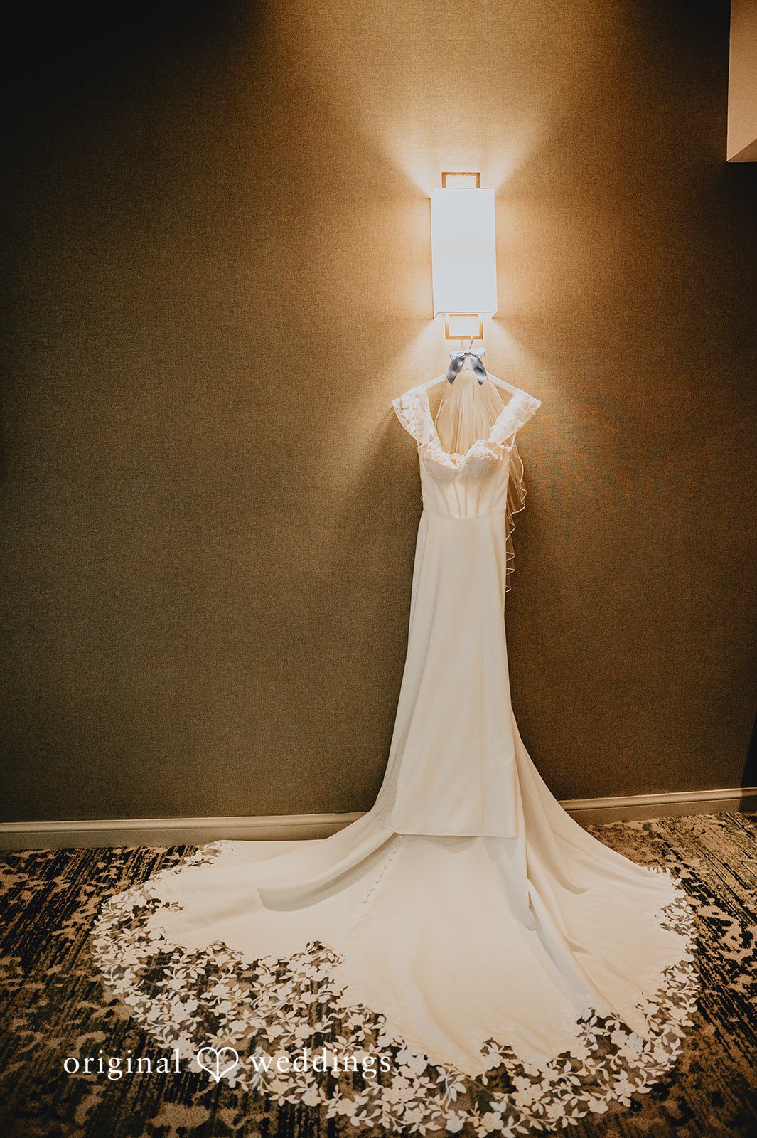 Elegant white wedding dress with a long train dramatically displayed against a dark background.