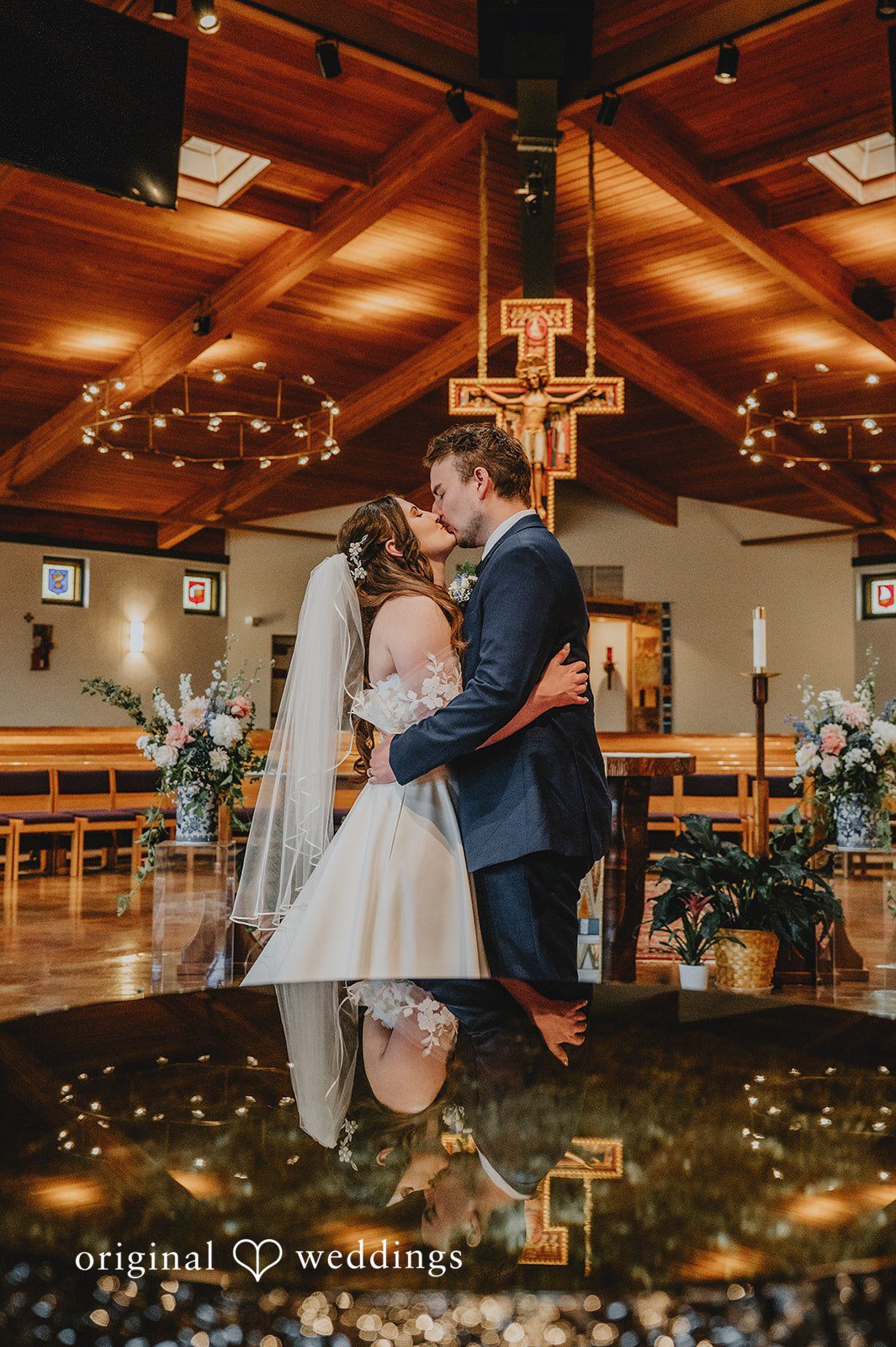 Bride and groom embracing and dipping for a kiss near the altar.