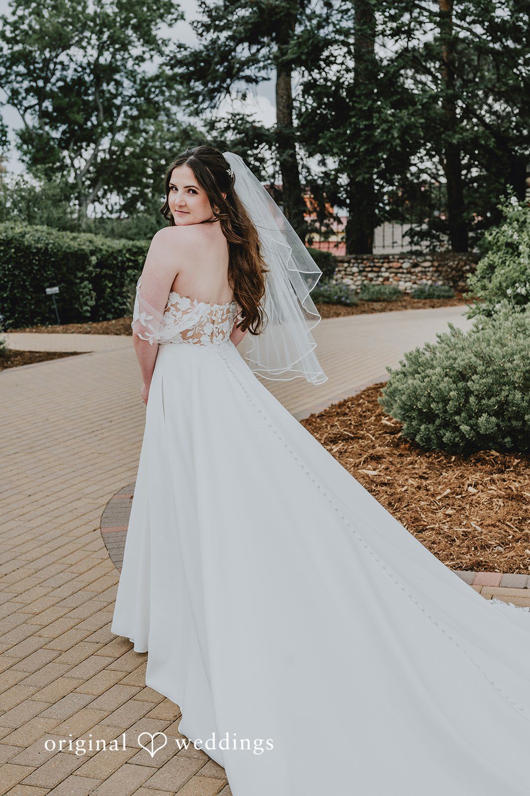 Full-length view of a bride walking down a path, displaying her long white veil.