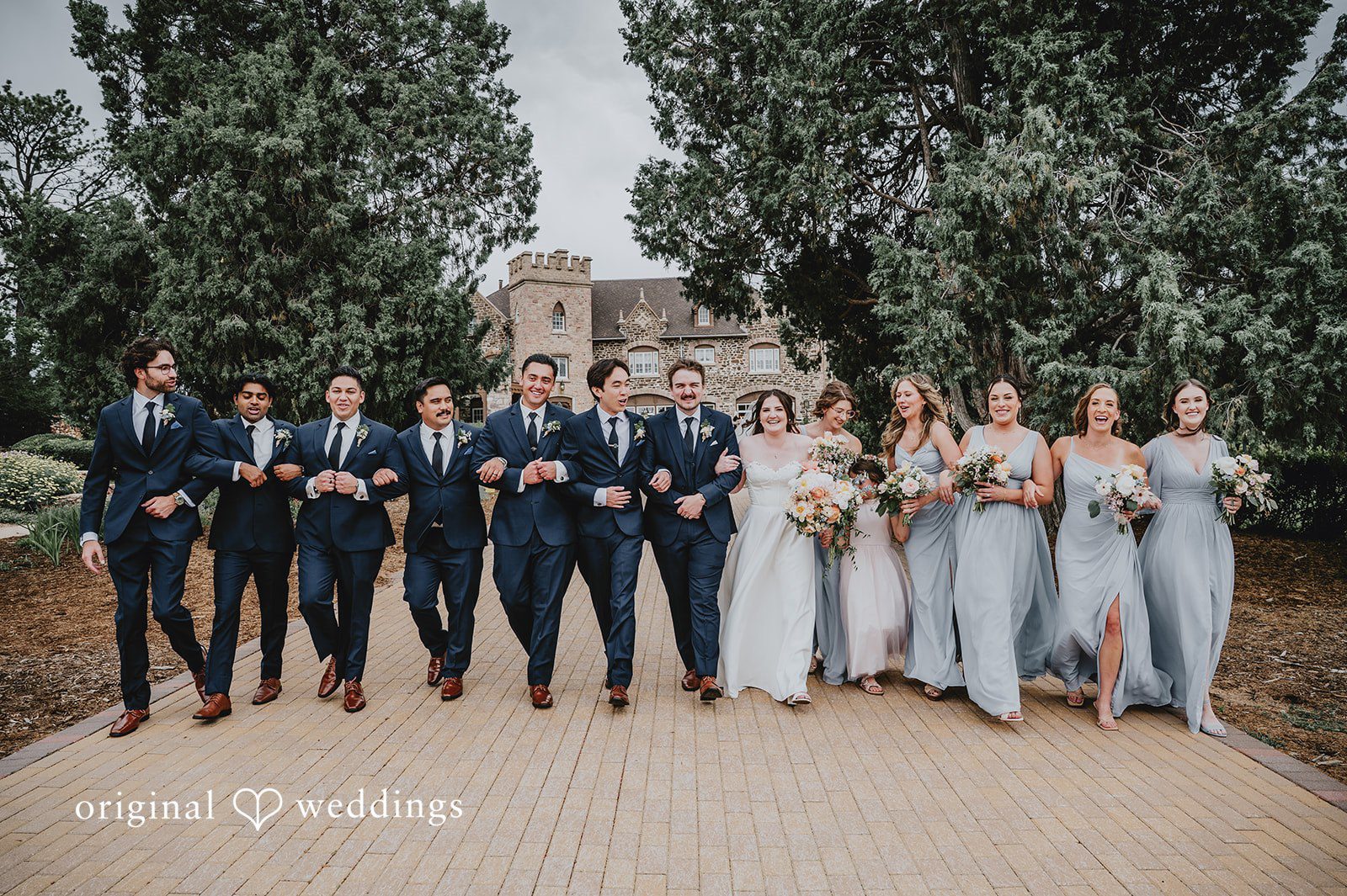 Groomsmen and bridesmaids standing in a line together outside.