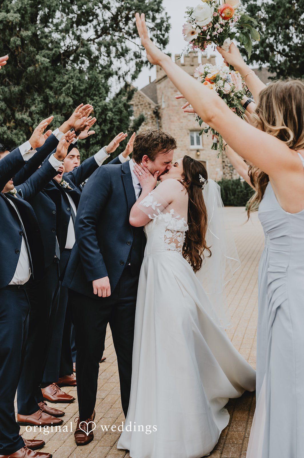 Newlyweds kissing as their wedding party cheers around them.