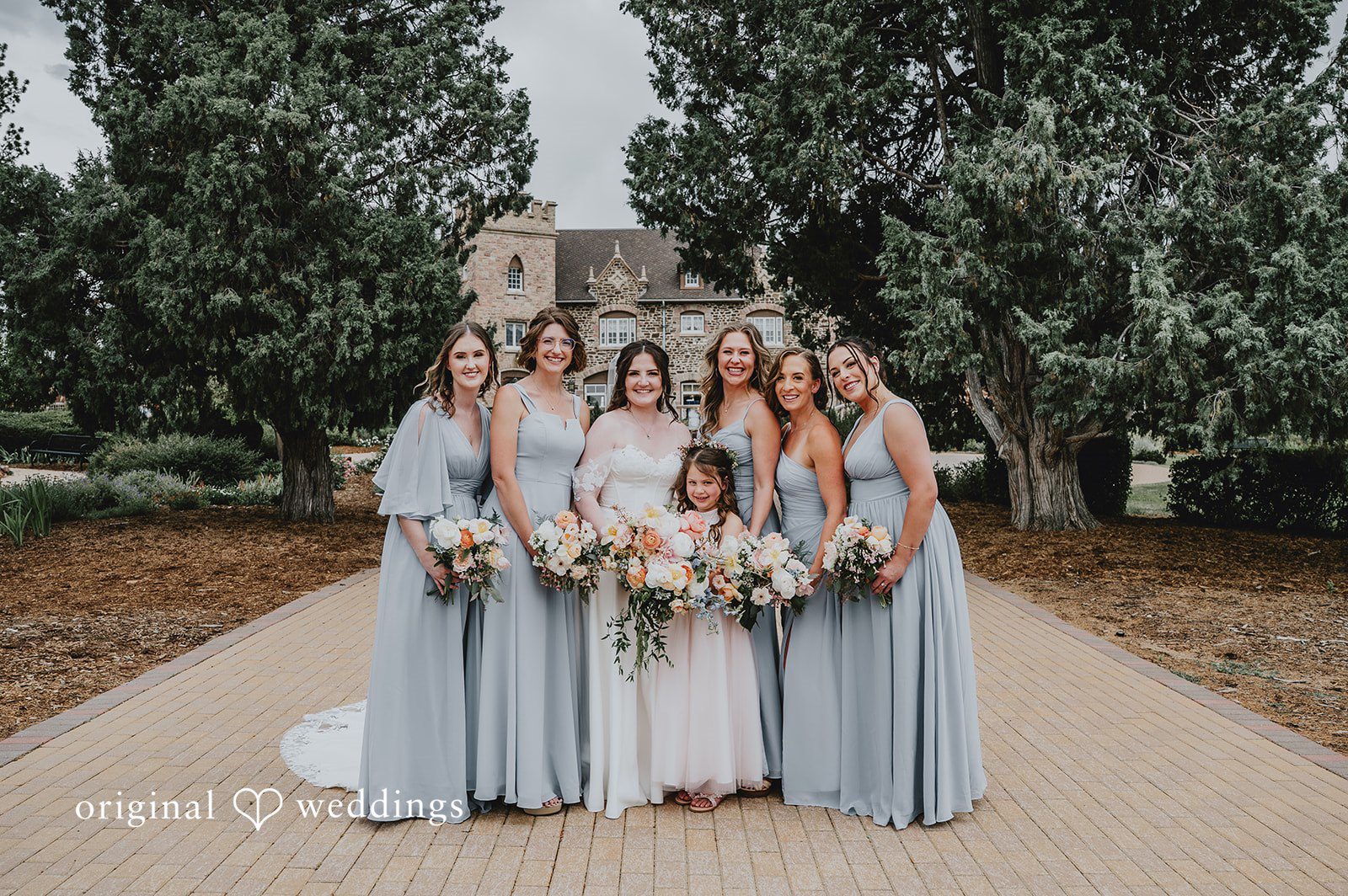 Bridesmaids in light blue dresses standing side-by-side holding floral bouquets.