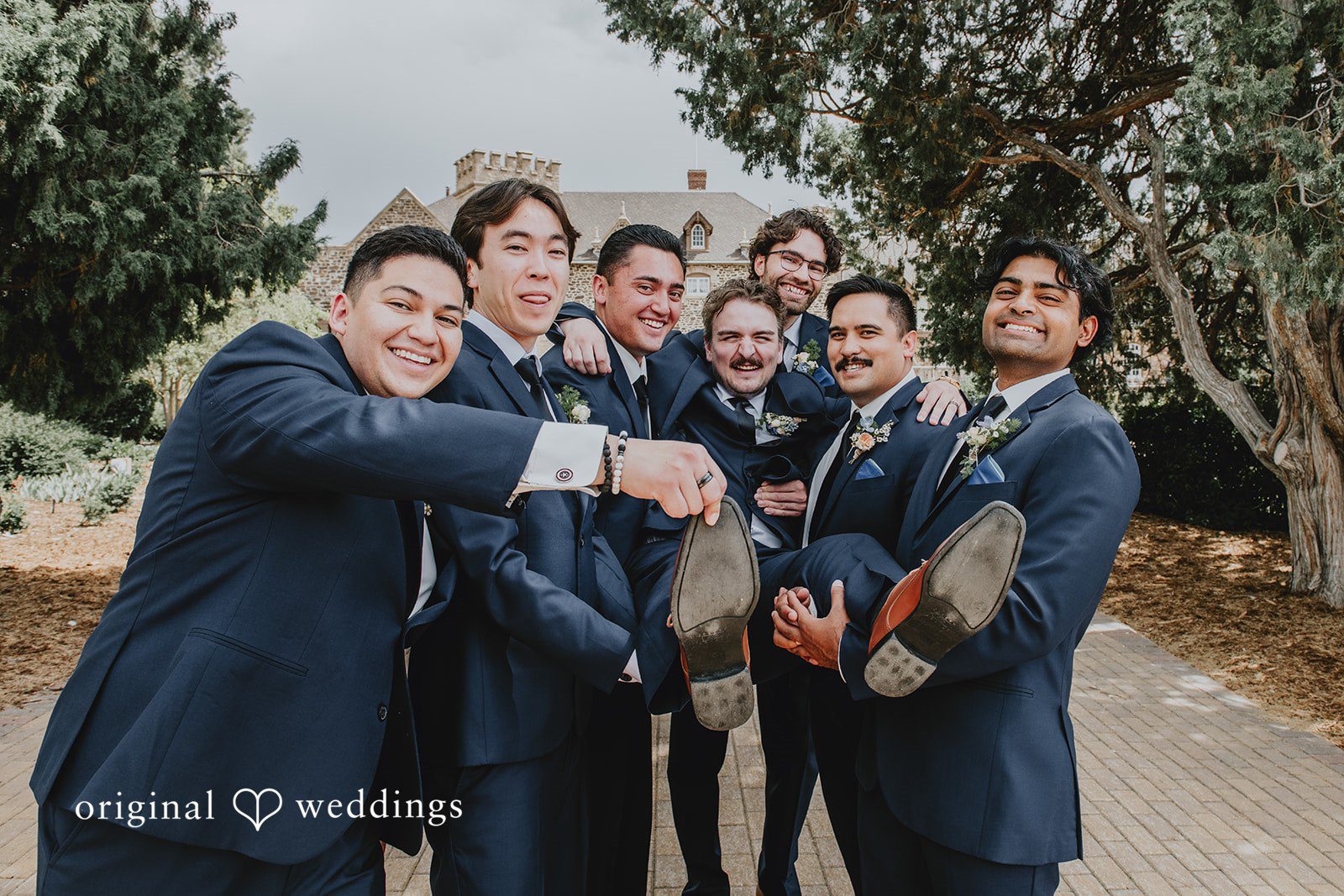 Groom and groomsmen smiling and cheering together before the ceremony.
