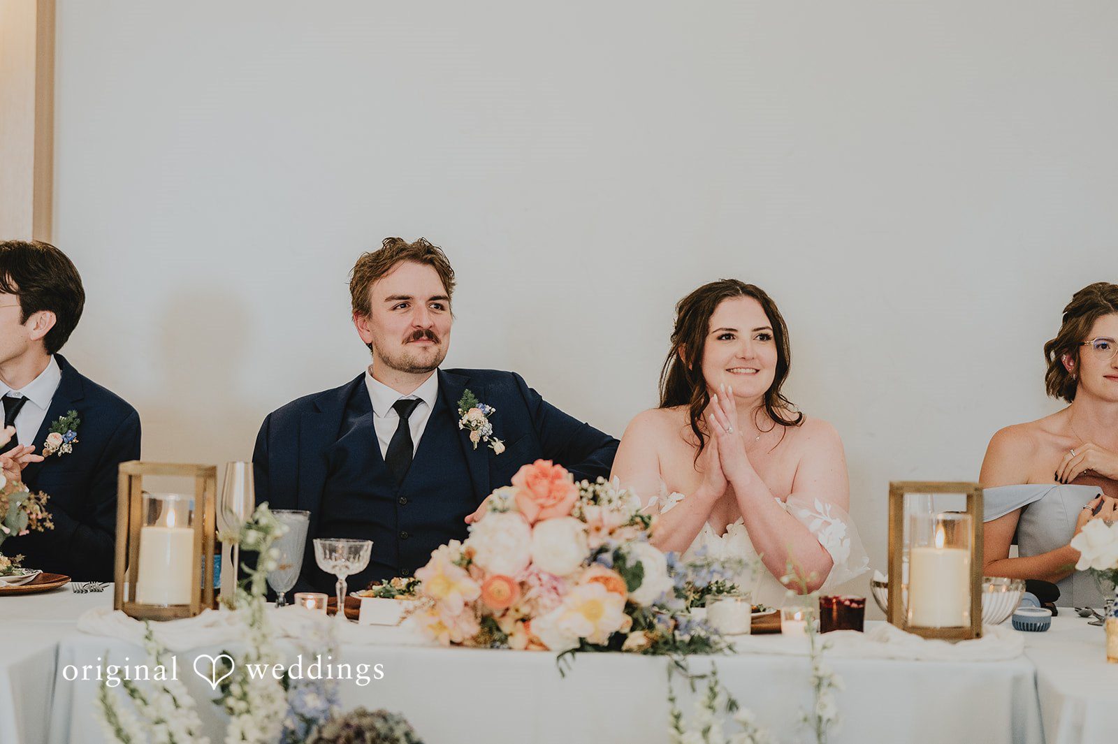 Bride and groom sitting together  at their reception table.