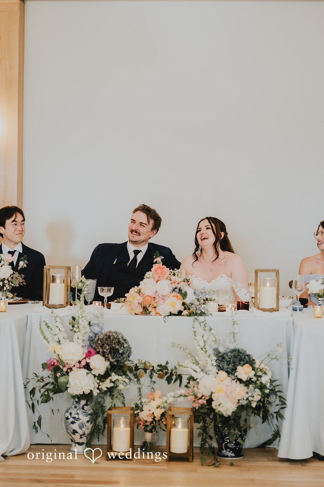 Bride and groom sitting together and laughing at their reception table.