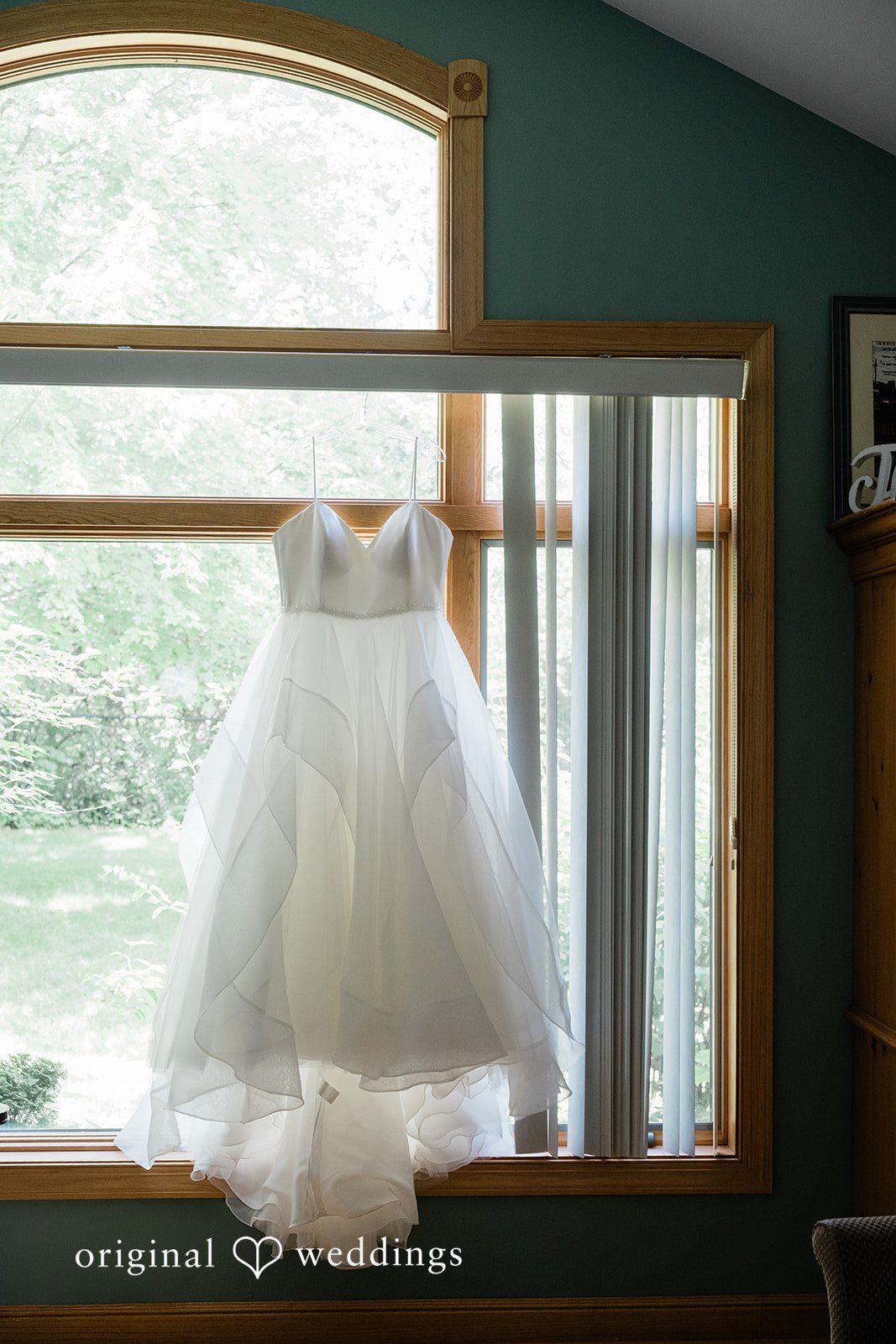 Carly + Seamus White wedding dress hanging in front of a mirror reflection.