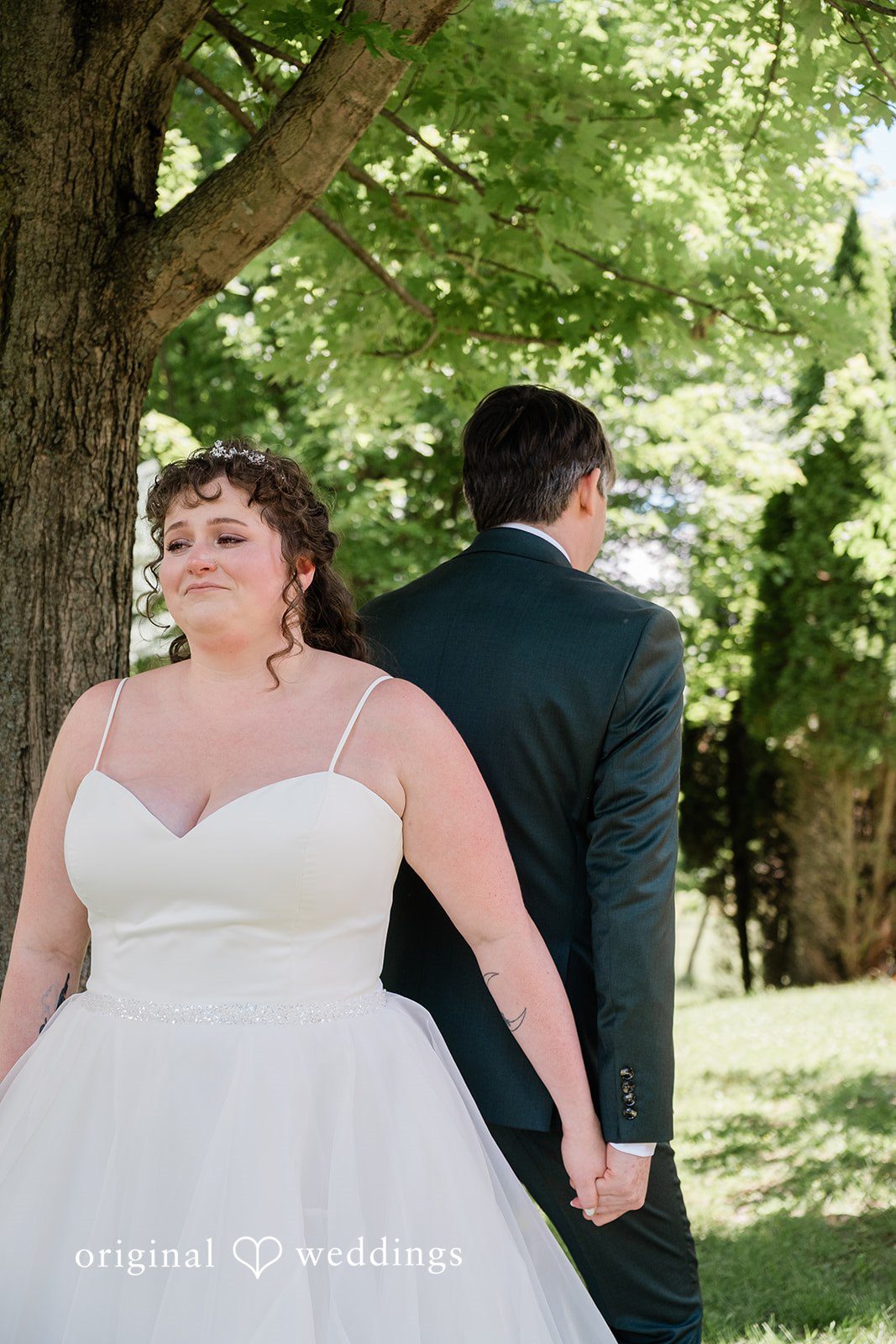 Carly + Seamus Bride holding the groom's hand as they walk away together on a lawn.