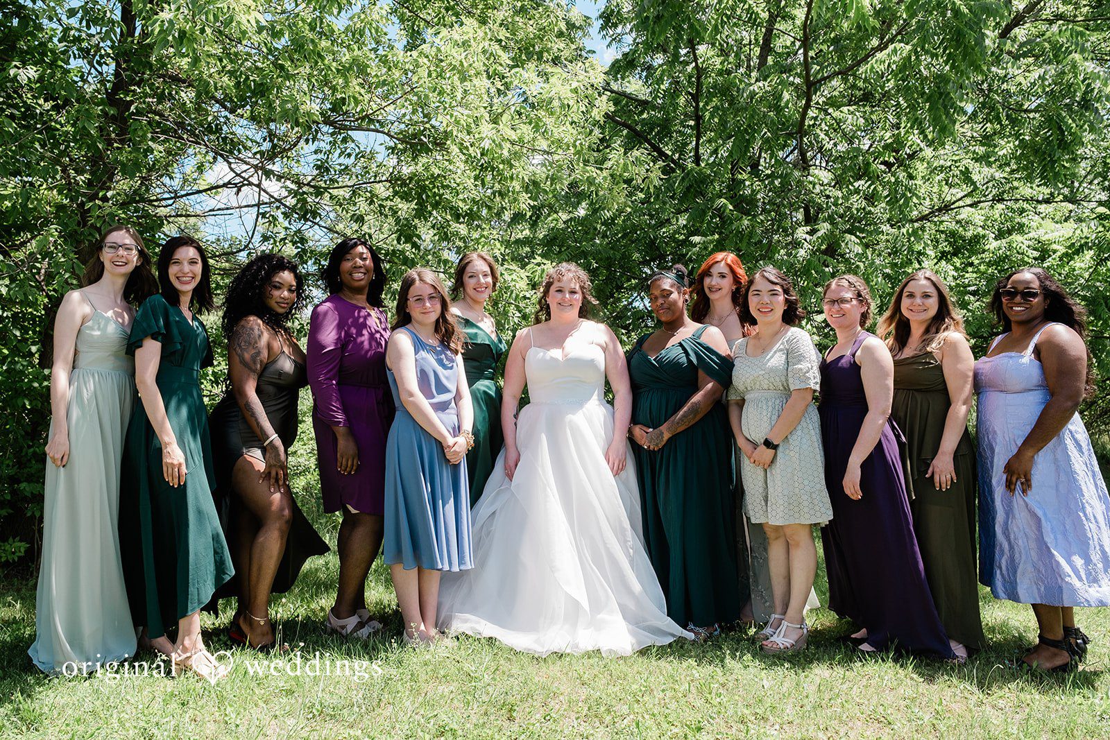 Carly + Seamus Group of bridesmaids in colorful dresses cheering on a lawn.