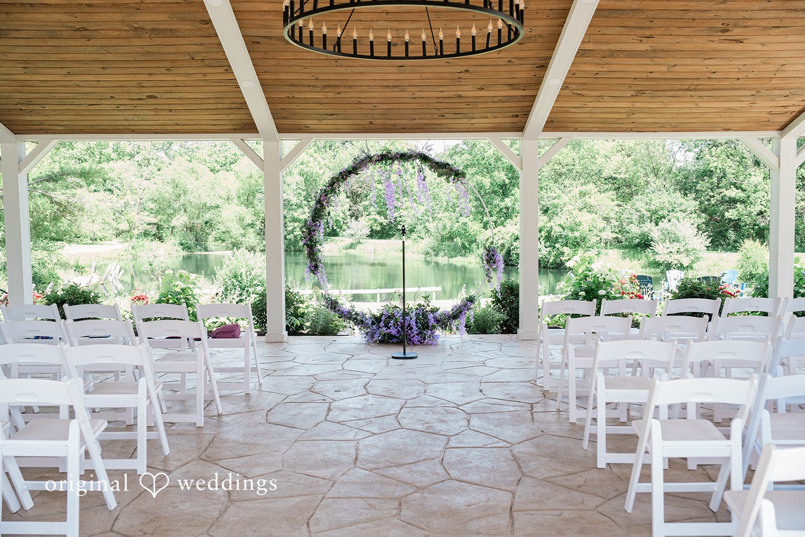 Carly + Seamus Open pavilion arranged with rows of white chairs facing a circular floral arch.
