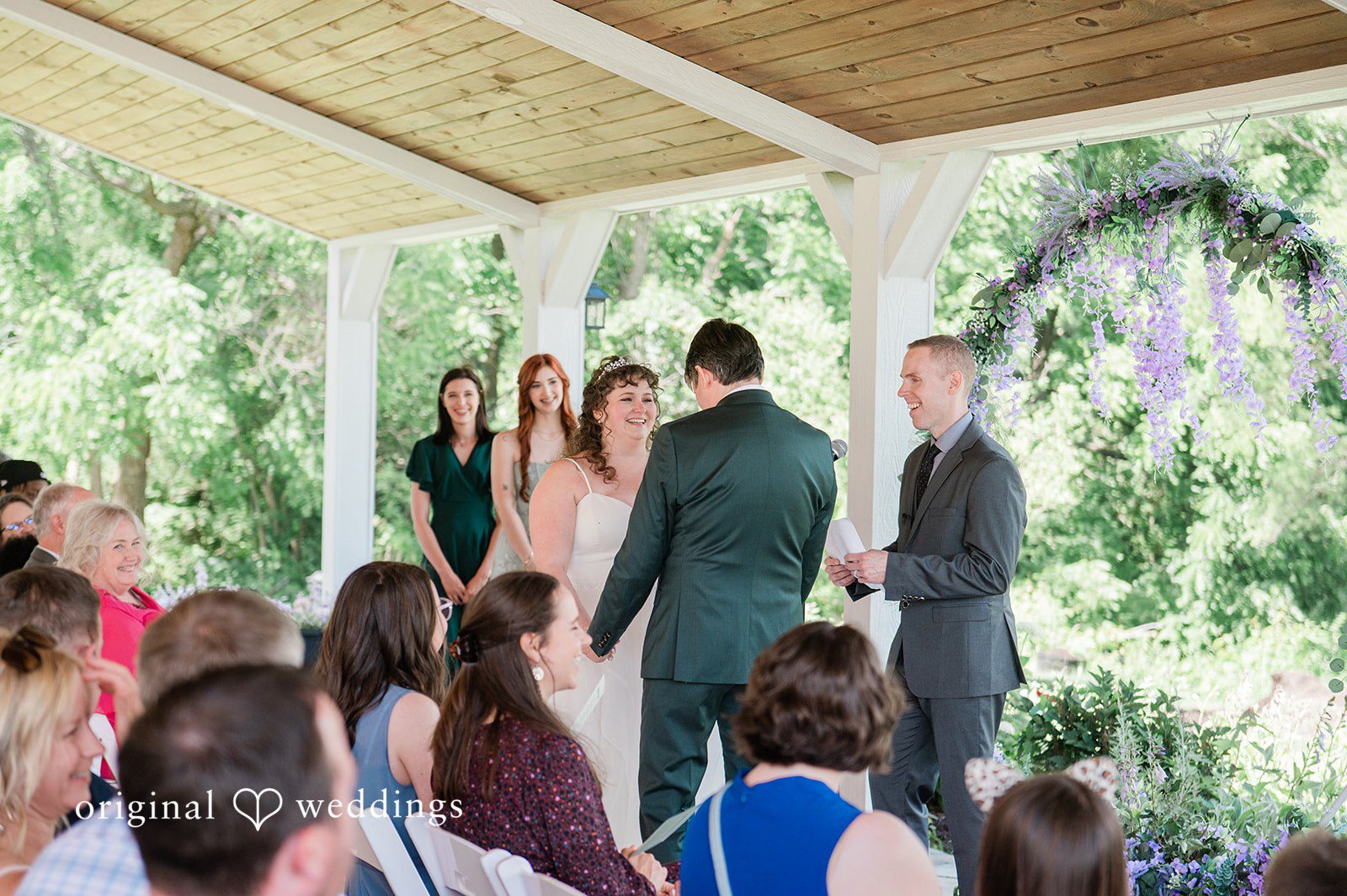 Carly + Seamus Wedding ceremony taking place under a decorated pavilion with seated guests.