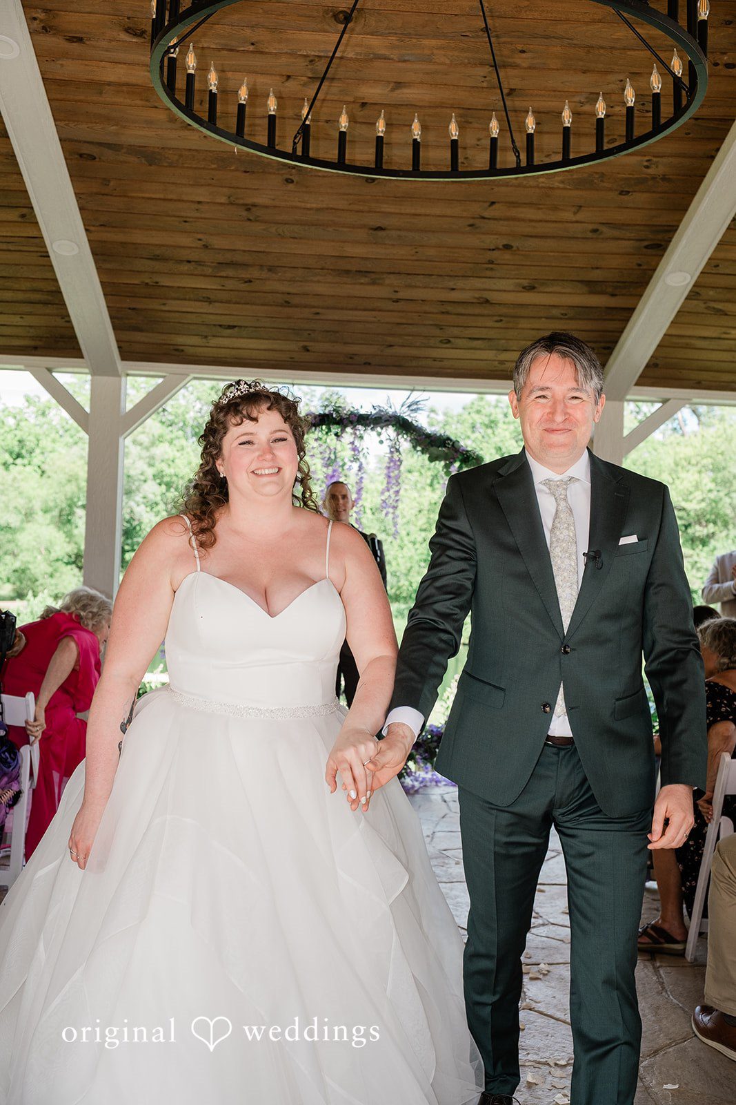 Carly + Seamus Smiling bride and groom holding hands while walking down the aisle.