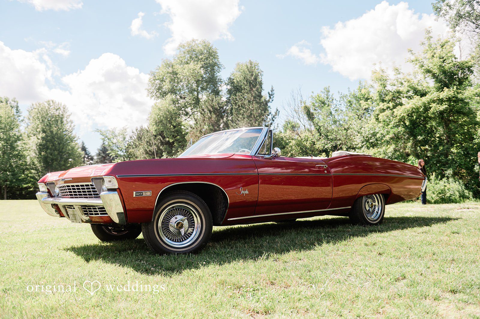 Carly + Seamus Vintage red convertible car parked on a grassy field.