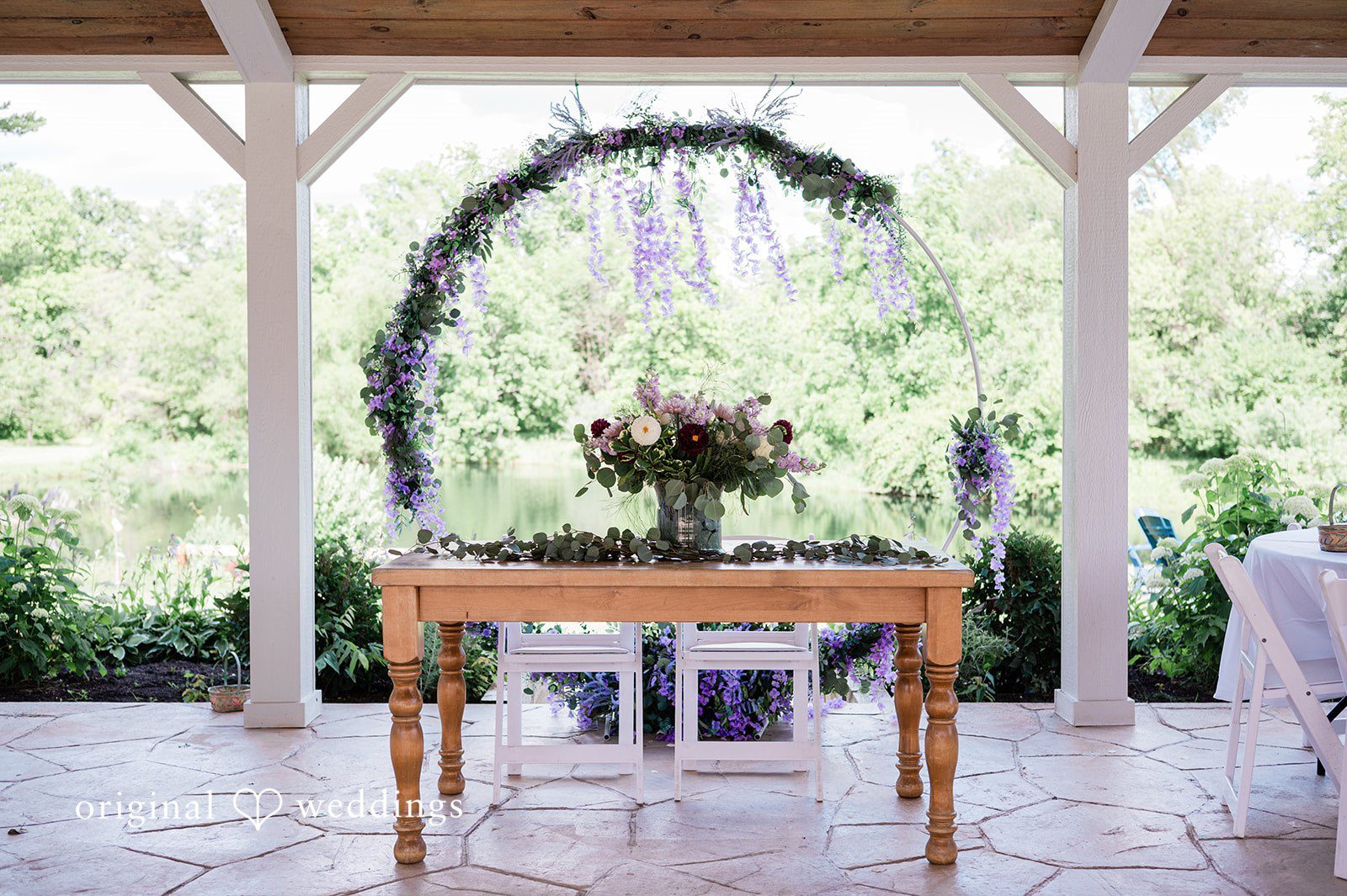 Carly + Seamus Wooden ceremony altar table decorated with flowers under a circular arch.