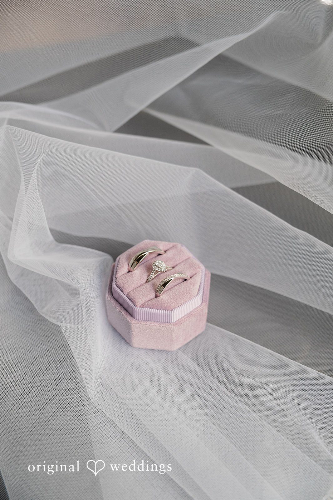 Carly + Seamus Small pink ring box resting on folds of white tulle fabric.