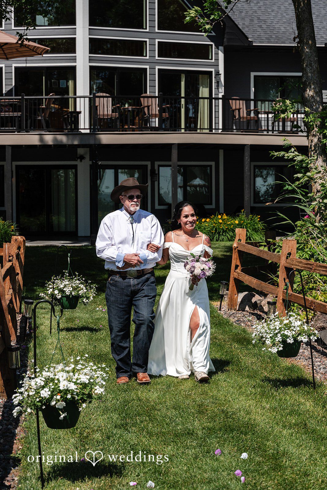 Wedding guests walking down a set of wooden stairs toward a grassy path.