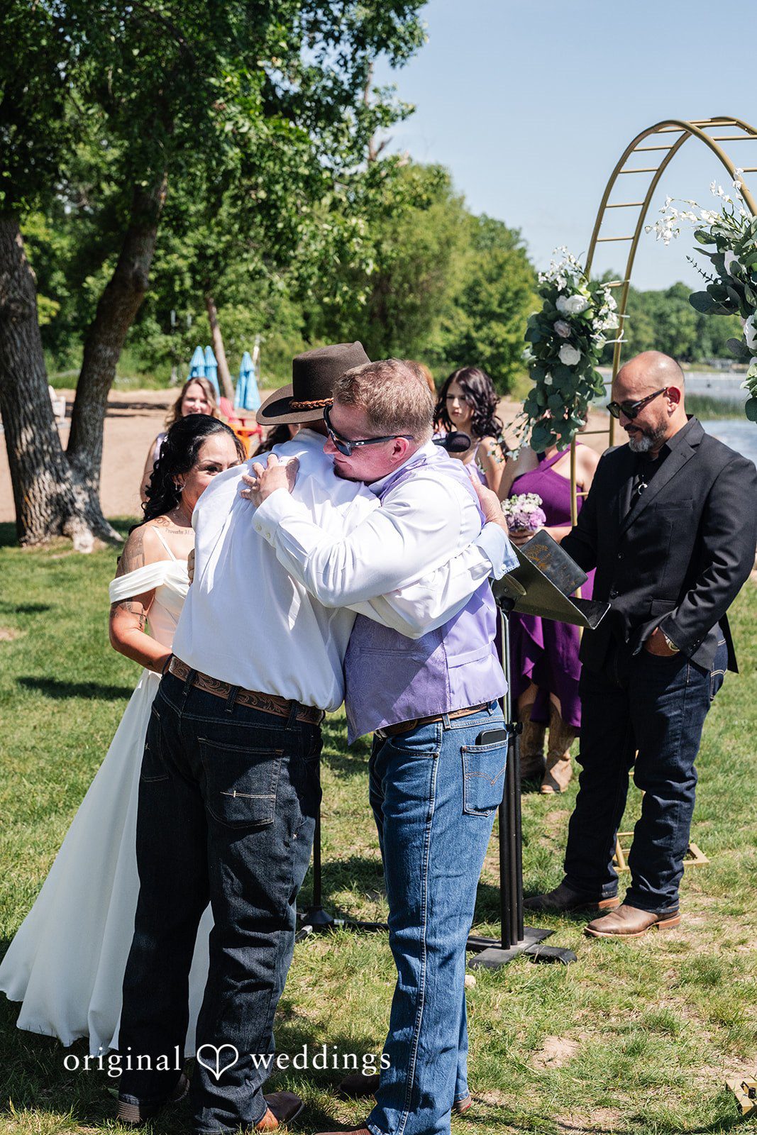 Two individuals sharing a joyful embrace during an event with onlookers nearby.