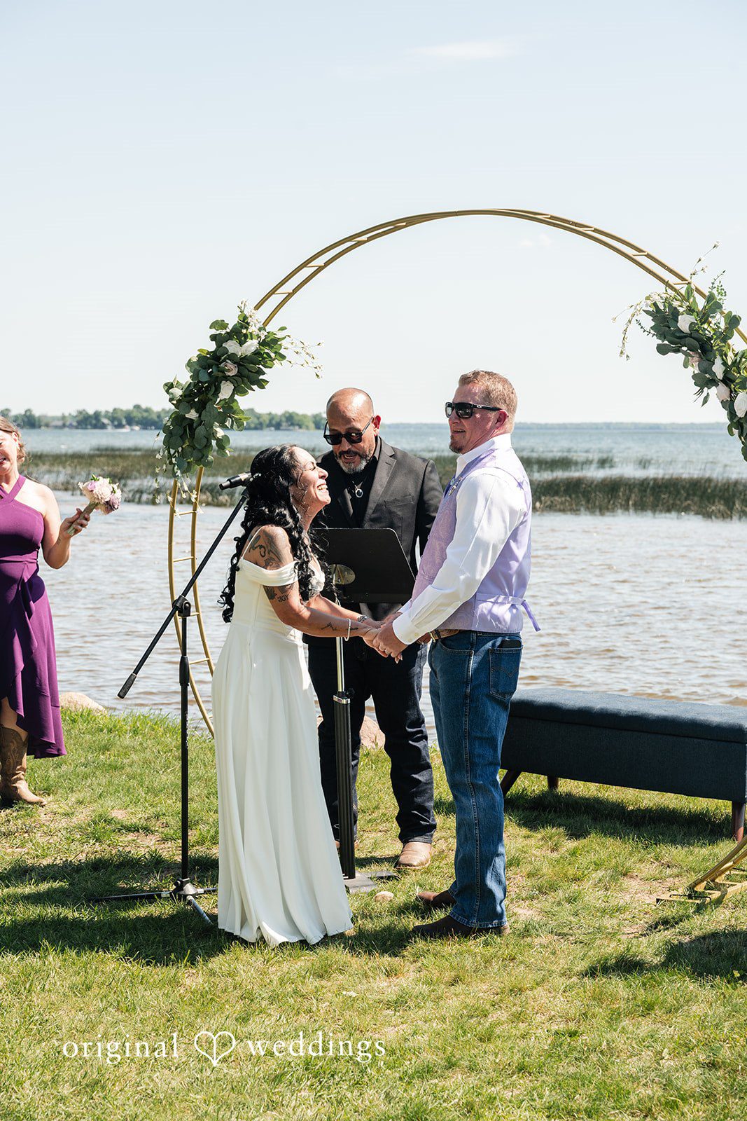A bride and groom holding hands under a large wooden circular archway.