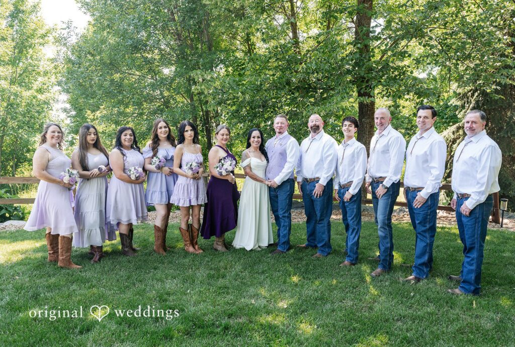 A wedding party of bridesmaids and groomsmen lined up together on a grassy field captured by Minneapolis Wedding Photographers from Original Weddings.