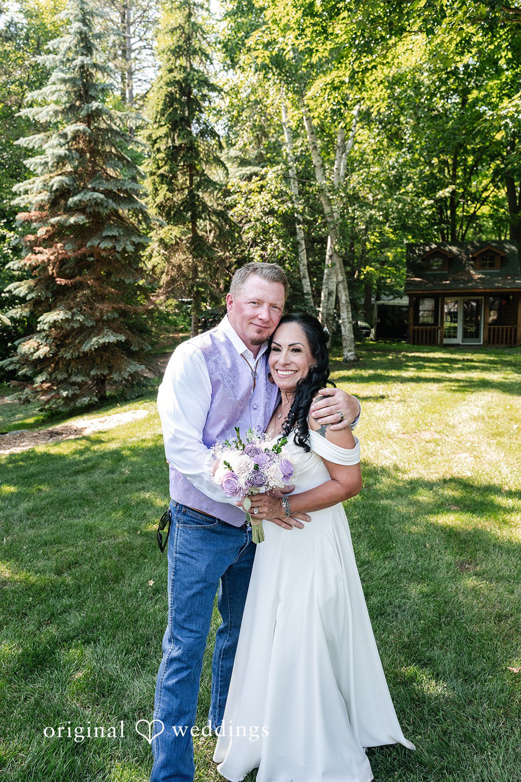 A man in a purple vest and a woman in a white dress standing on a grassy lawn.