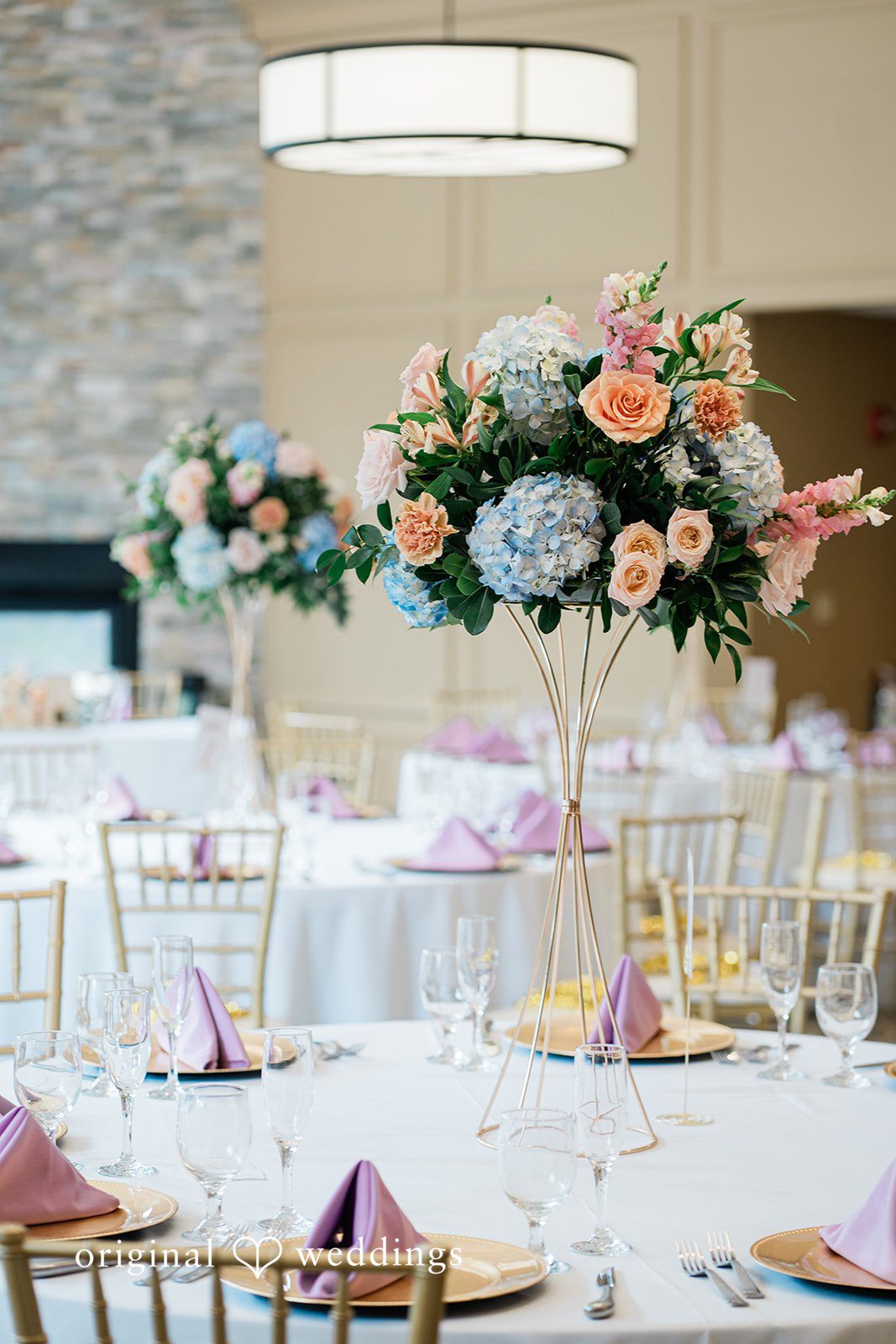 Jessica + Patrick A wedding reception table featuring a tall, colorful floral arrangement.