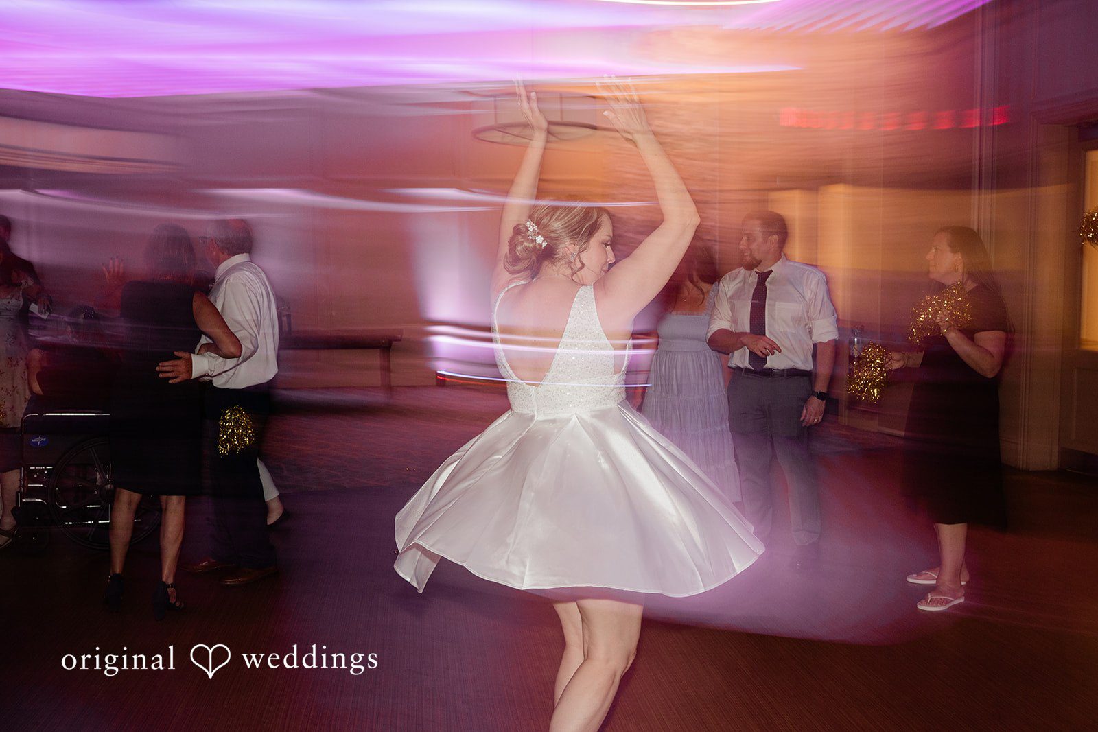 Jessica + Patrick A blurred motion shot of a bride spinning around on a dimly lit dance floor.