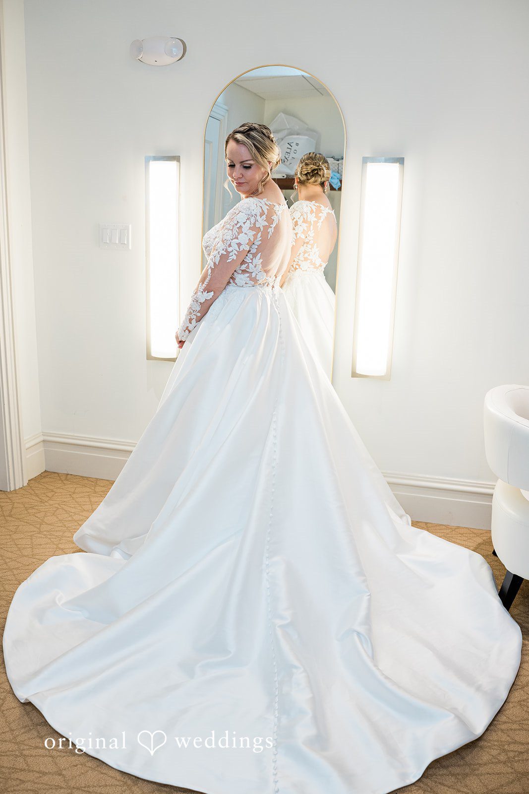 Jessica + Patrick A full-length view from behind of a bride showcasing the long train of her white gown.