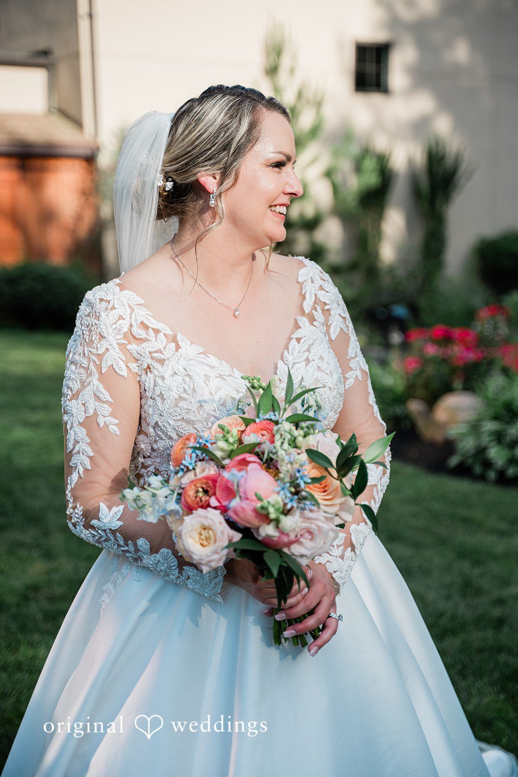 Jessica + Patrick A smiling bride looking down while holding a colorful wedding bouquet.