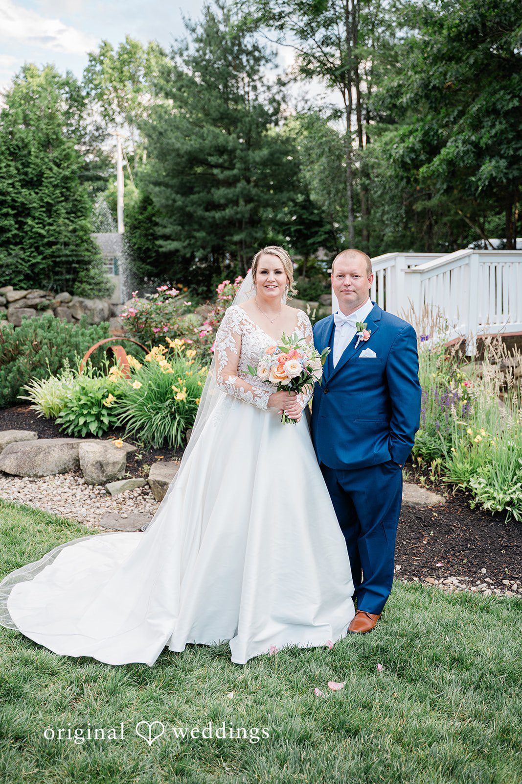 Jessica + Patrick A bride and groom pose together on a lawn with a garden background.